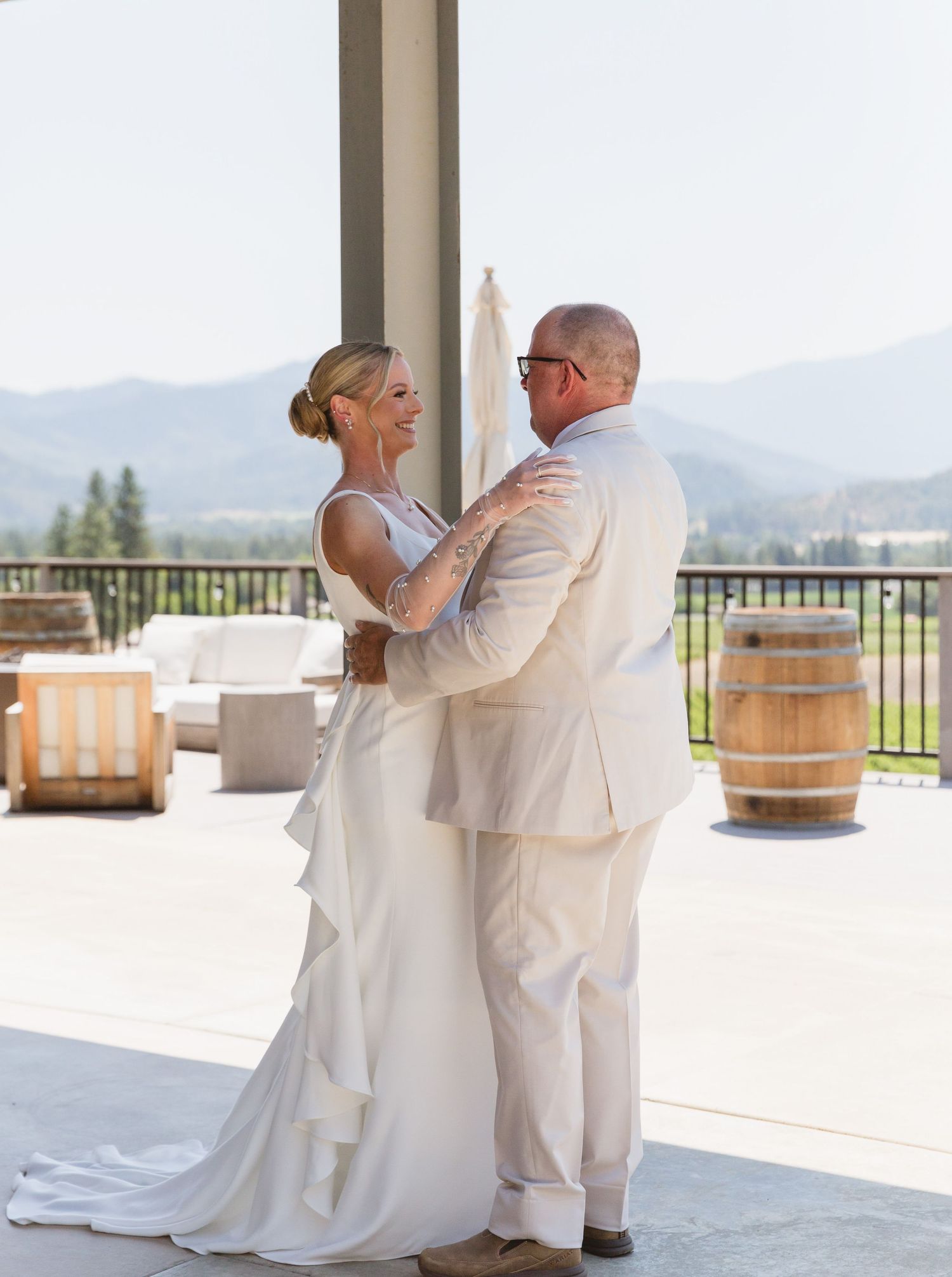 A couple shares their first dance on an outdoor terrace overlooking scenic mountain views at a winery wedding.