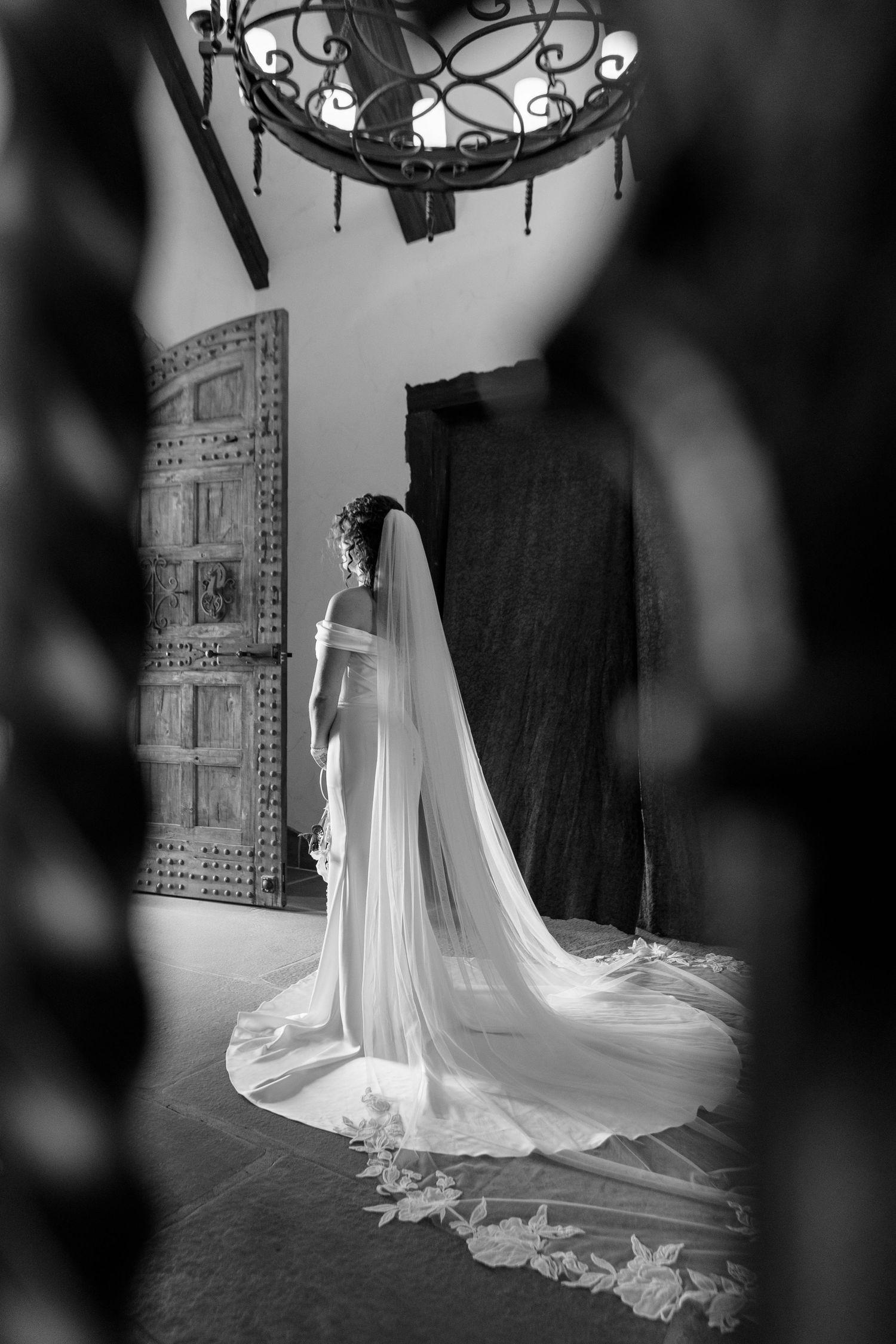 Beautiful cathedral-length wedding veil trailing on stone flooring in dramatic black and white photography.