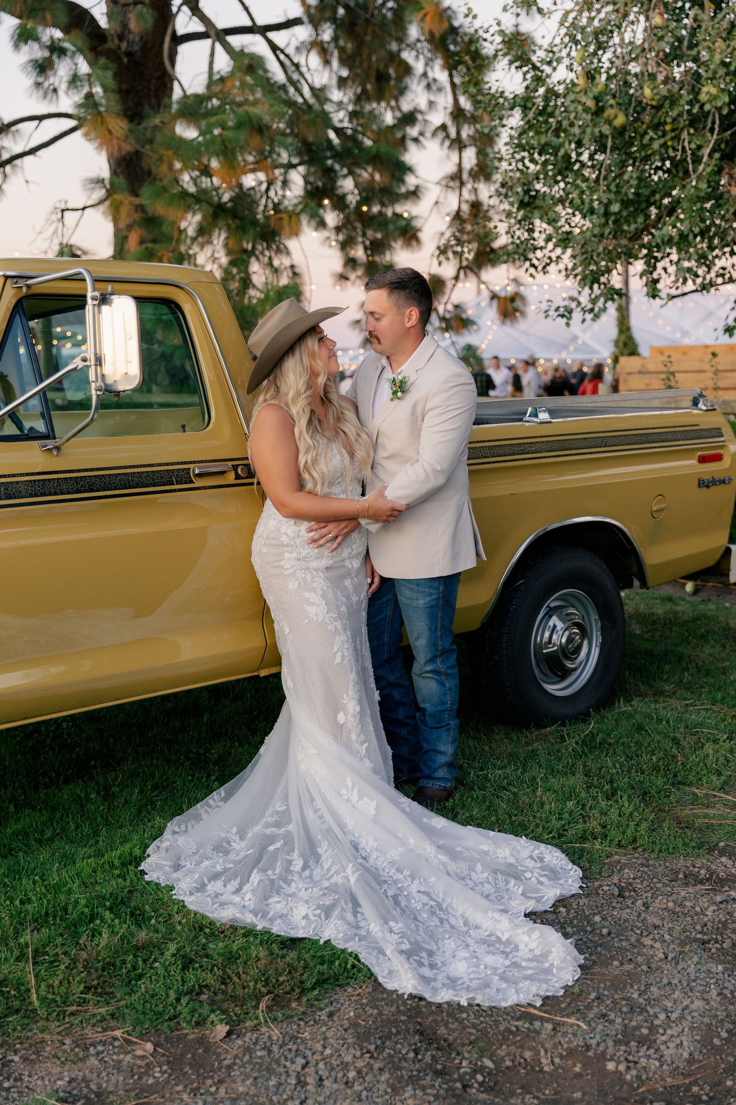 A romantic country wedding scene with a vintage gold pickup truck in a scenic outdoor setting.