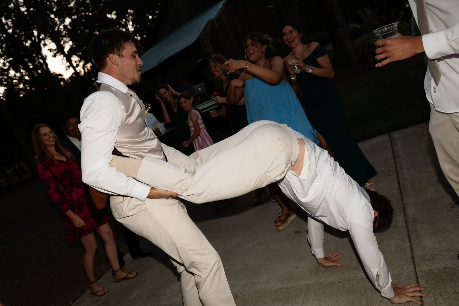 Guests dancing energetically at an outdoor wedding reception at night.