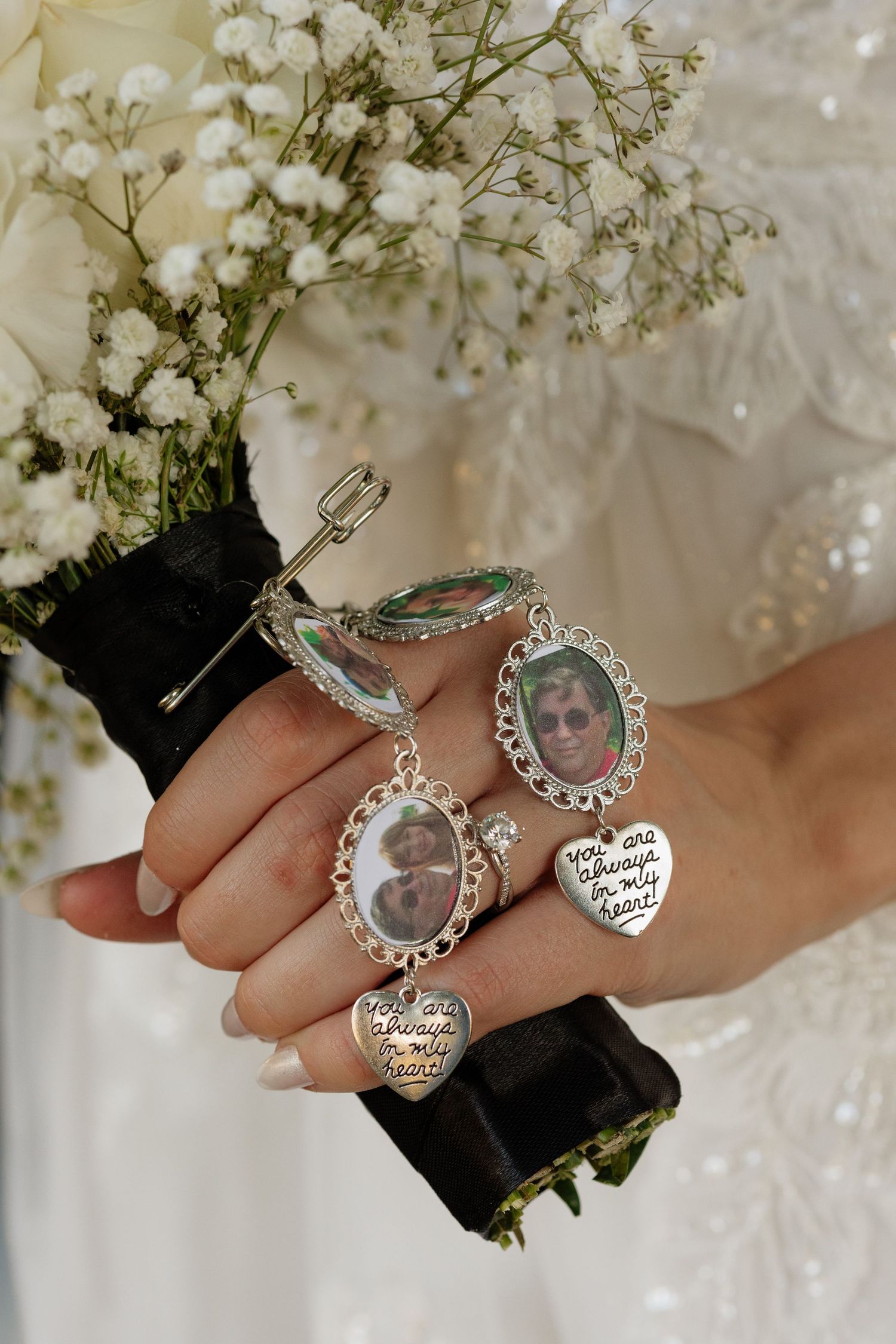 Close-up of bridal bouquet handle with memorial photo charms and heart pendants honoring loved ones.