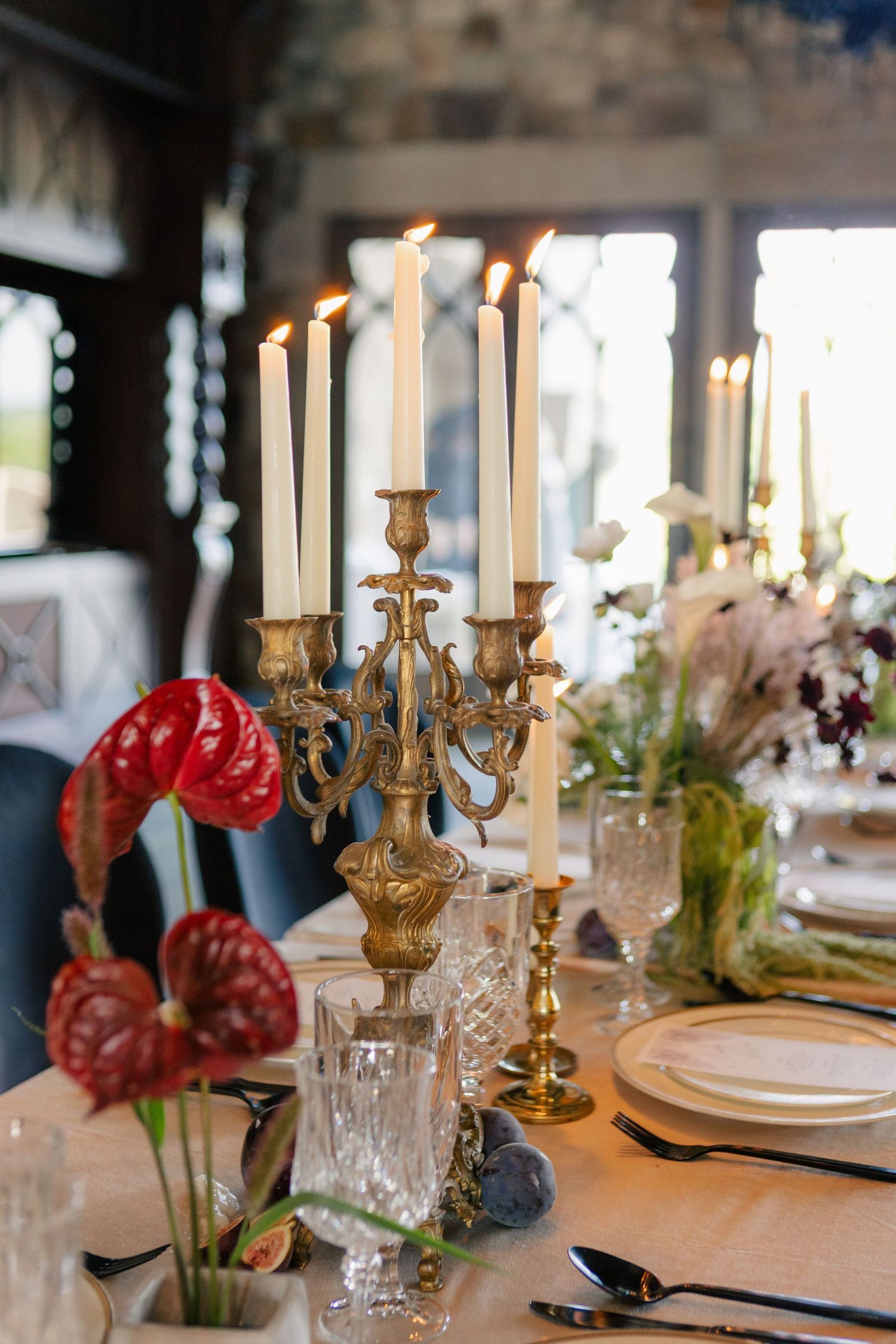 Elegant table settings with gold candelabras, crystal glasses, and delicate floral arrangements for a formal dining event.