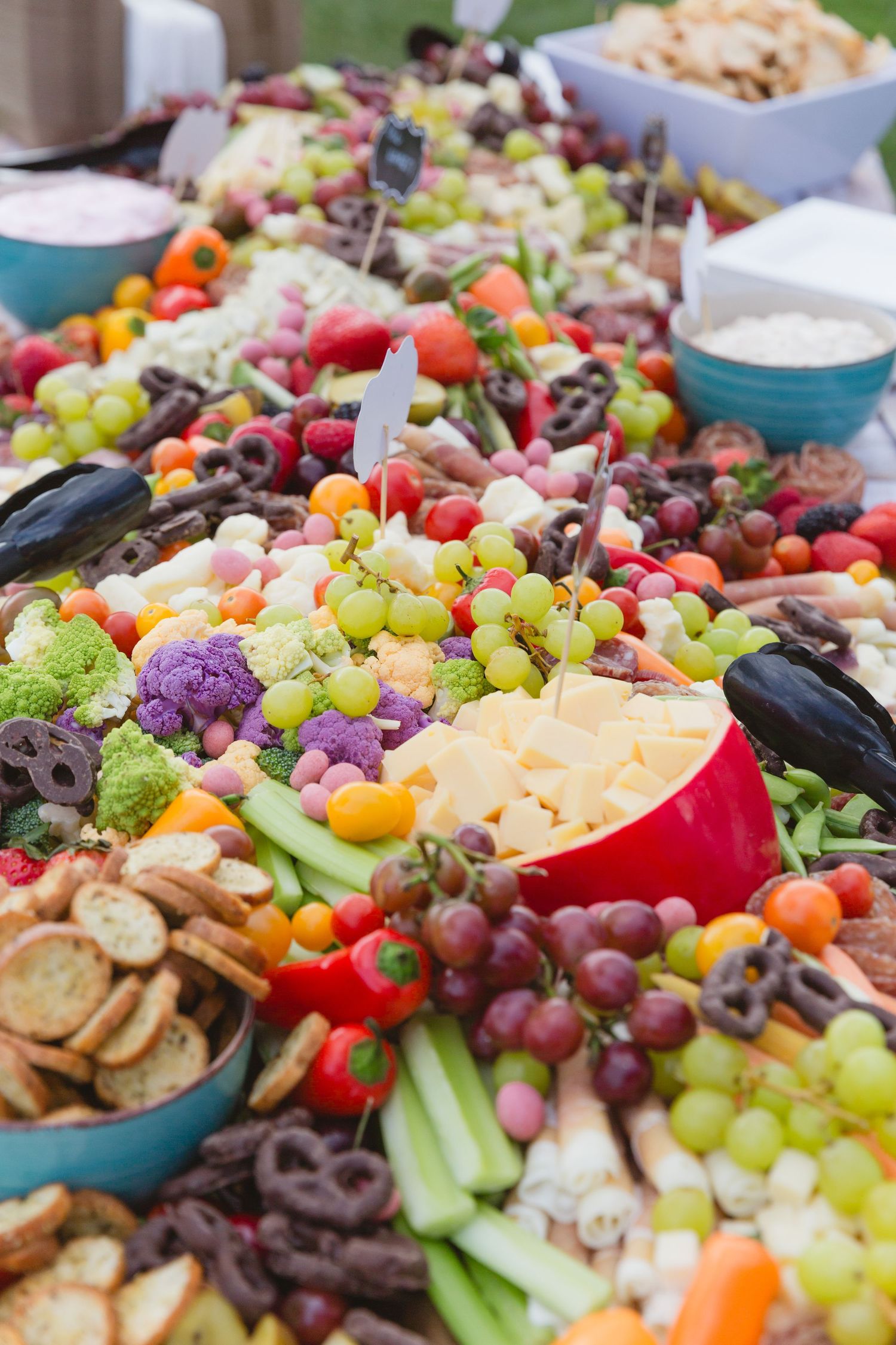 A vibrant charcuterie board filled with fresh fruits, cheeses, crackers, and olives arranged in colorful patterns.