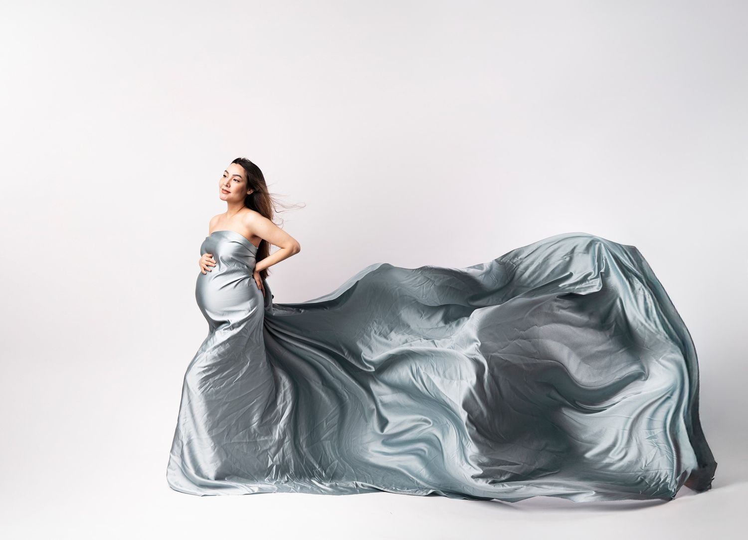 Artistic maternity photos with flowing silver fabric against white background.