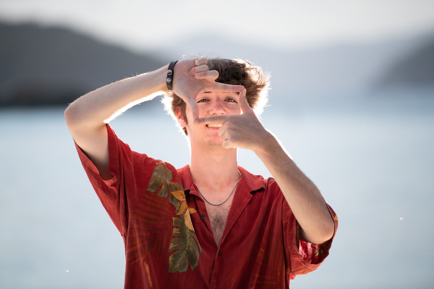 High school senior boy photographed with bold directional light on a St. John overlook at sunset.