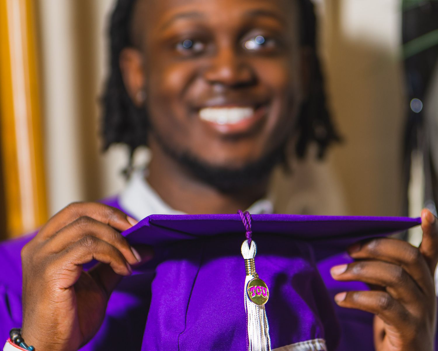 TCU senior man posing with cap and gown during a portrait session with Sean Stacey.