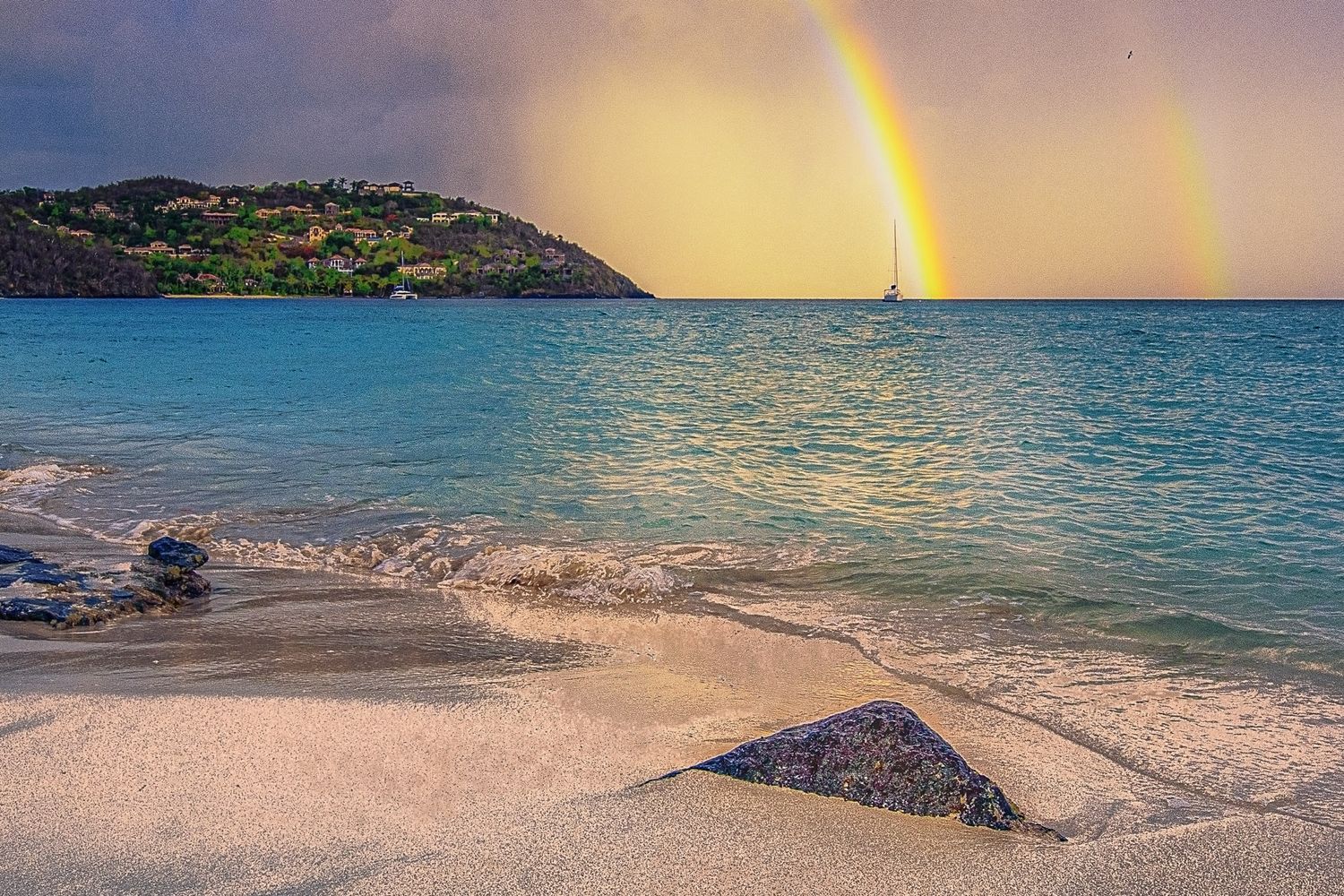 A rainbow and turquoise waters at sunrise over Cinnamon Bay, USVI, taken by photographer Sean Stacey.