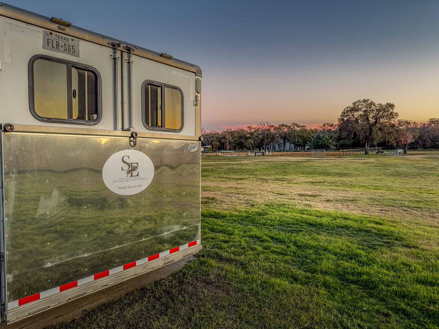 Behind the scenes private photography coverage of horse trailer parked on grass field during sunset at an equestrian center in Texas.