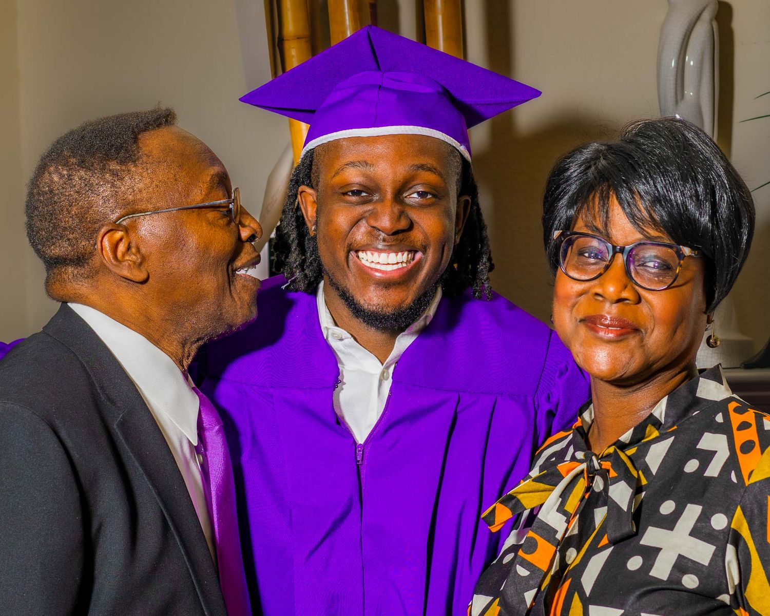 TCU senior celebrating at graduation ceremony wearing purple caps and gowns with family members.