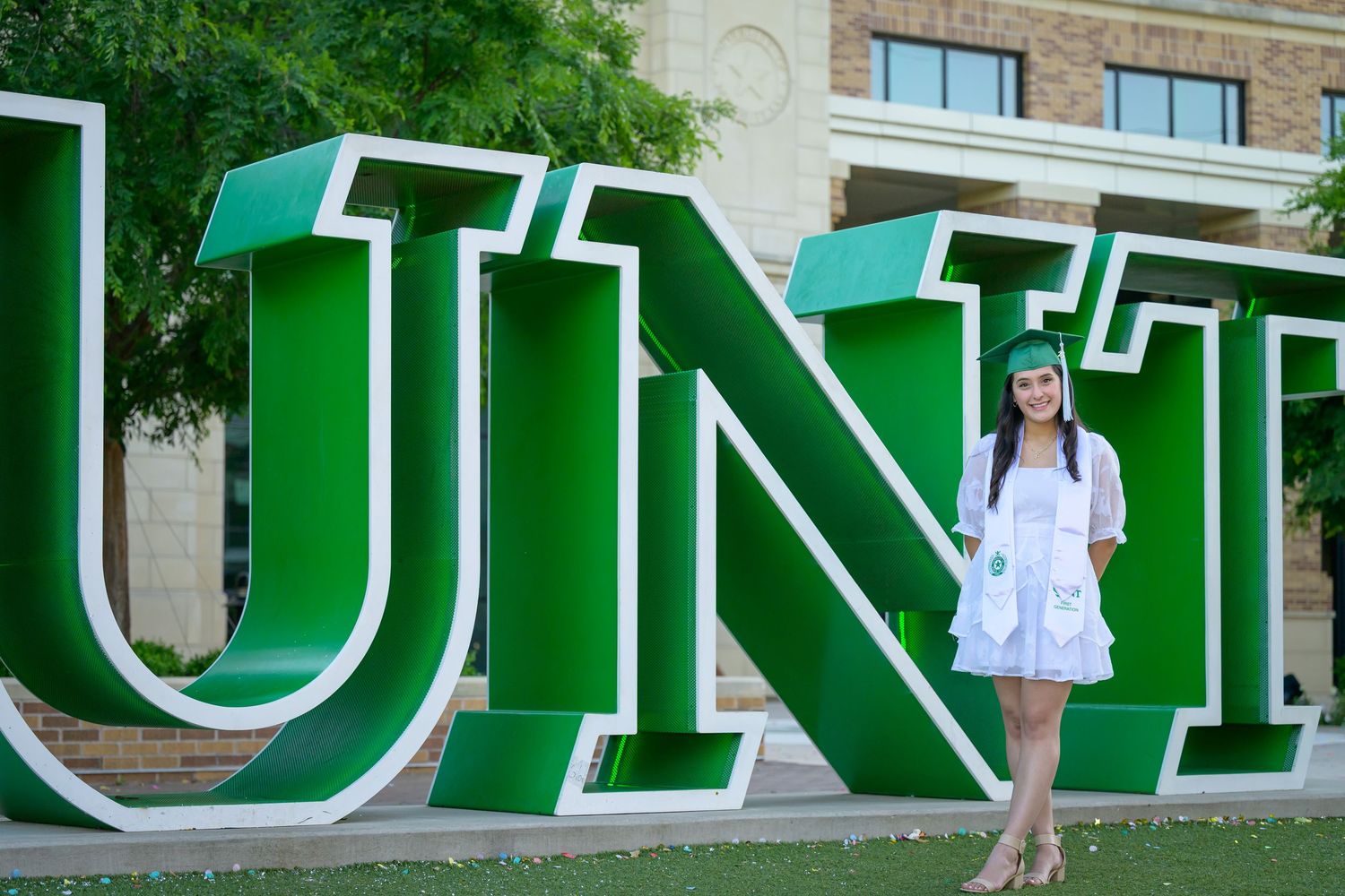Large green letters mounted on a stone building facade spell out text against an architectural background.