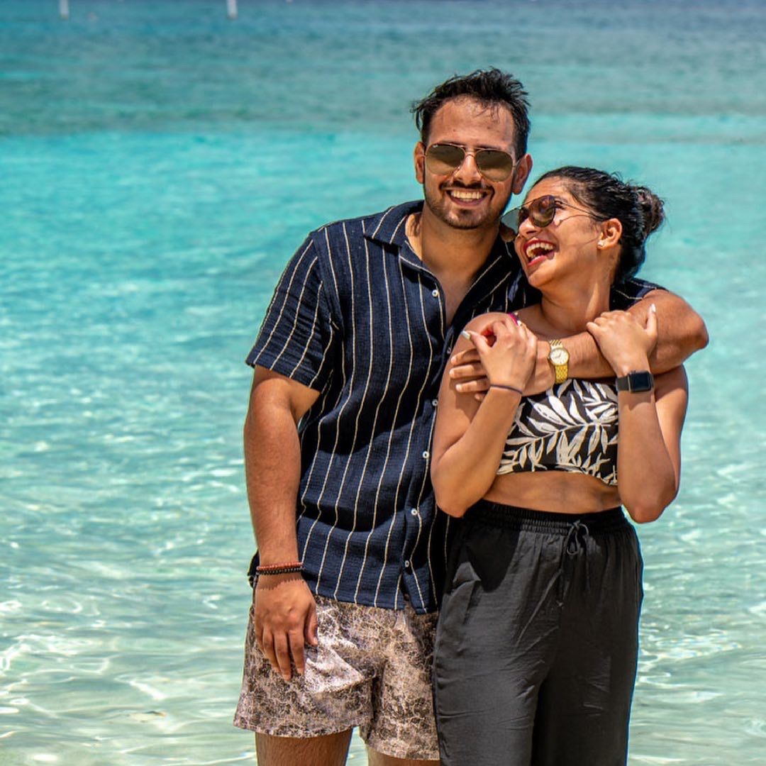 Happy couple enjoying a romantic moment together on a tropical beach with stunning turquoise water in the background.