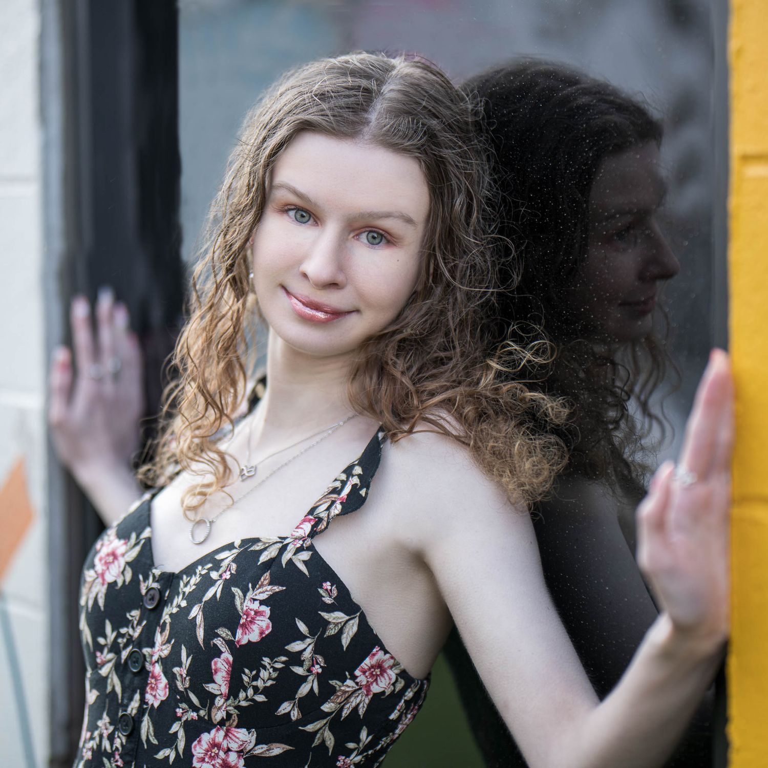 Senior girl in a floral dress poses against a dark background in a series of portraits taken by Sean Stacey.