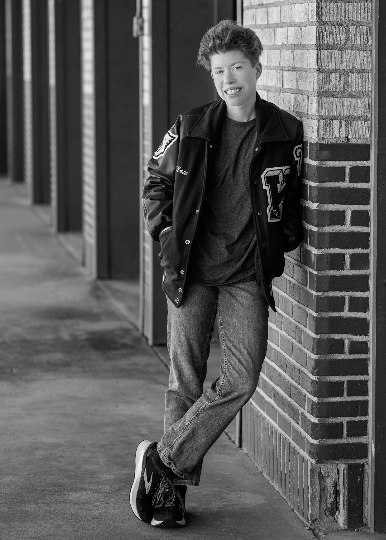 Black and white photo series showing a person in dark clothing leaning against a brick wall in different poses.