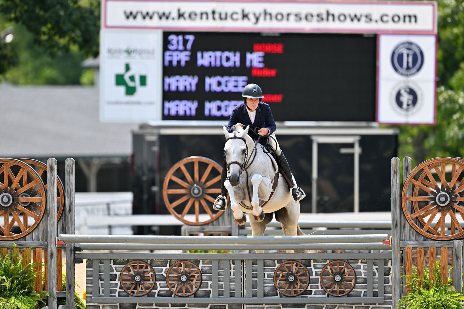 Horse and rider competing at Kentucky Horse Shows with electronic scoreboard visible.
