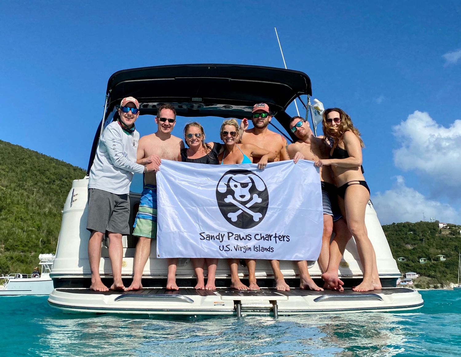 Group enjoying a boat trip in crystal clear turquoise waters near a tropical coastline on a sunny day.