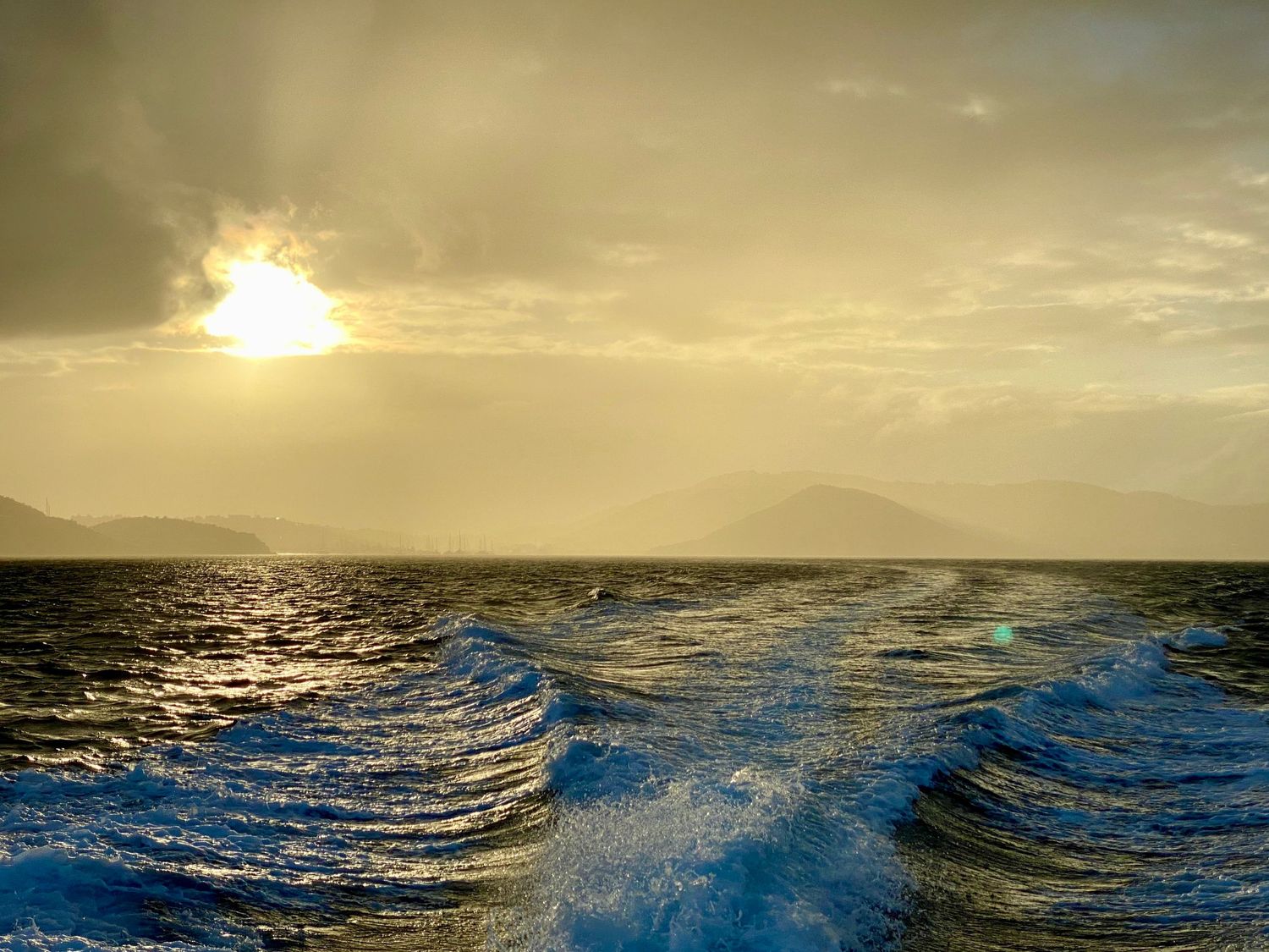 Dramatic sunset seascape with golden sky and rolling waves creating a moody ocean panorama.