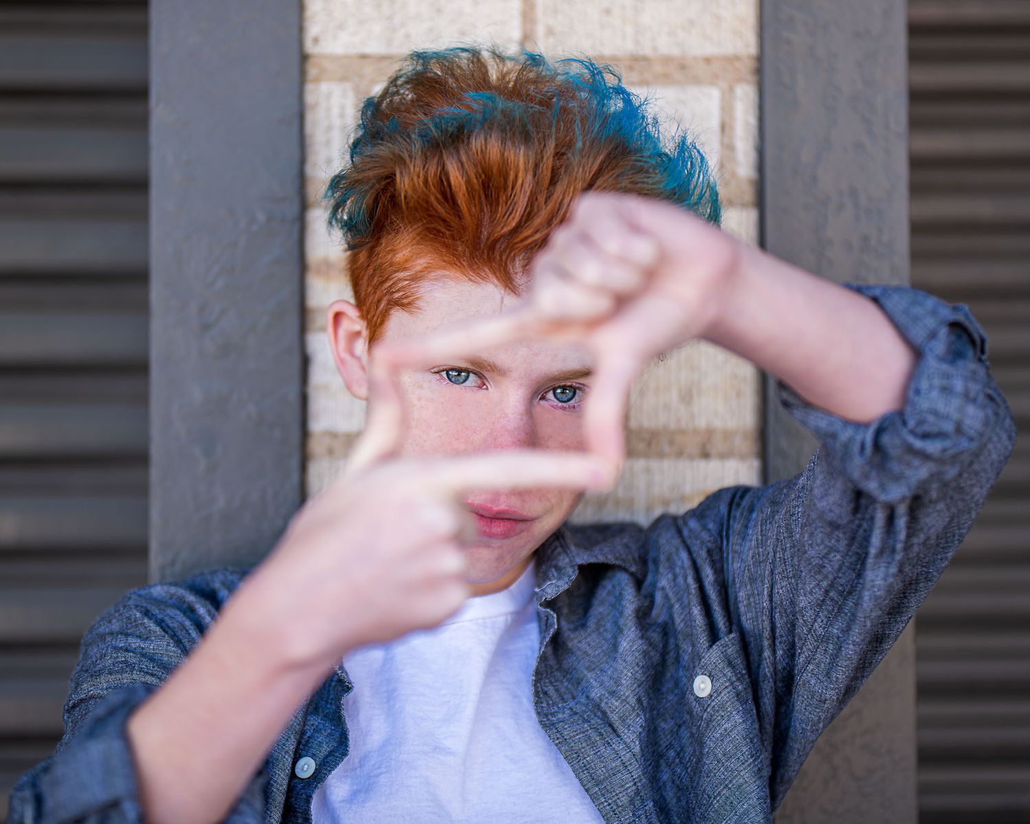 Graduating senior portrait session showing someone using hands to block their face while wearing a denim jacket.