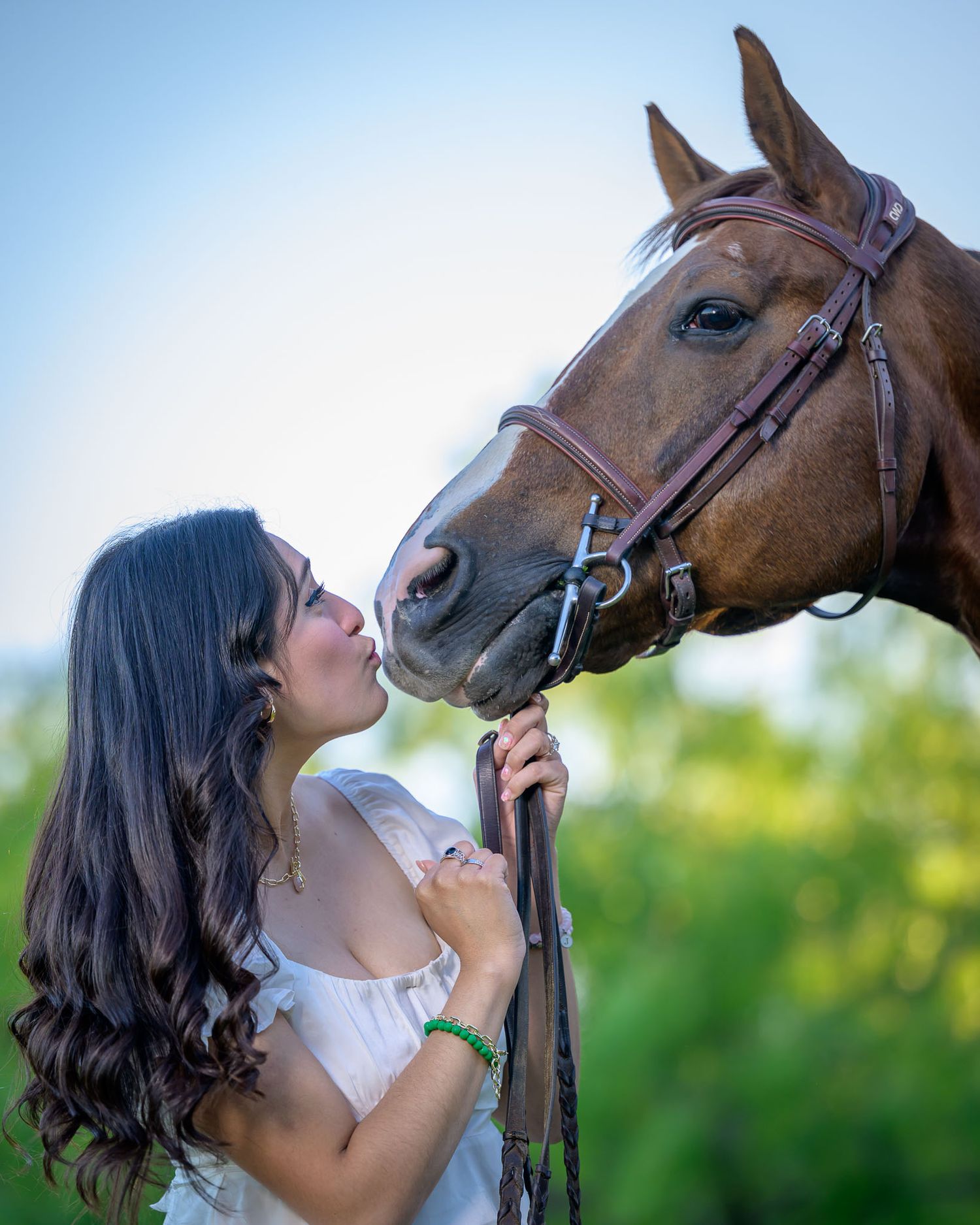 A tender moment between a rider and their brown horse in a sunlit outdoor setting.