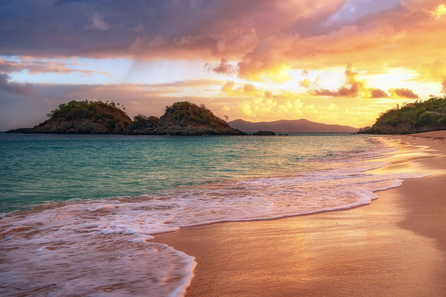 Dramatic orange and pink sunrise over a pristine tropical beach with gentle waves lapping at the sandy shore taken by Sean Stacey.