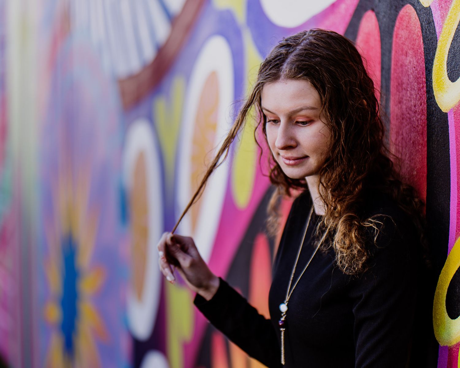 Artistic portraits against a vibrant graffiti wall with colorful pink and yellow designs.