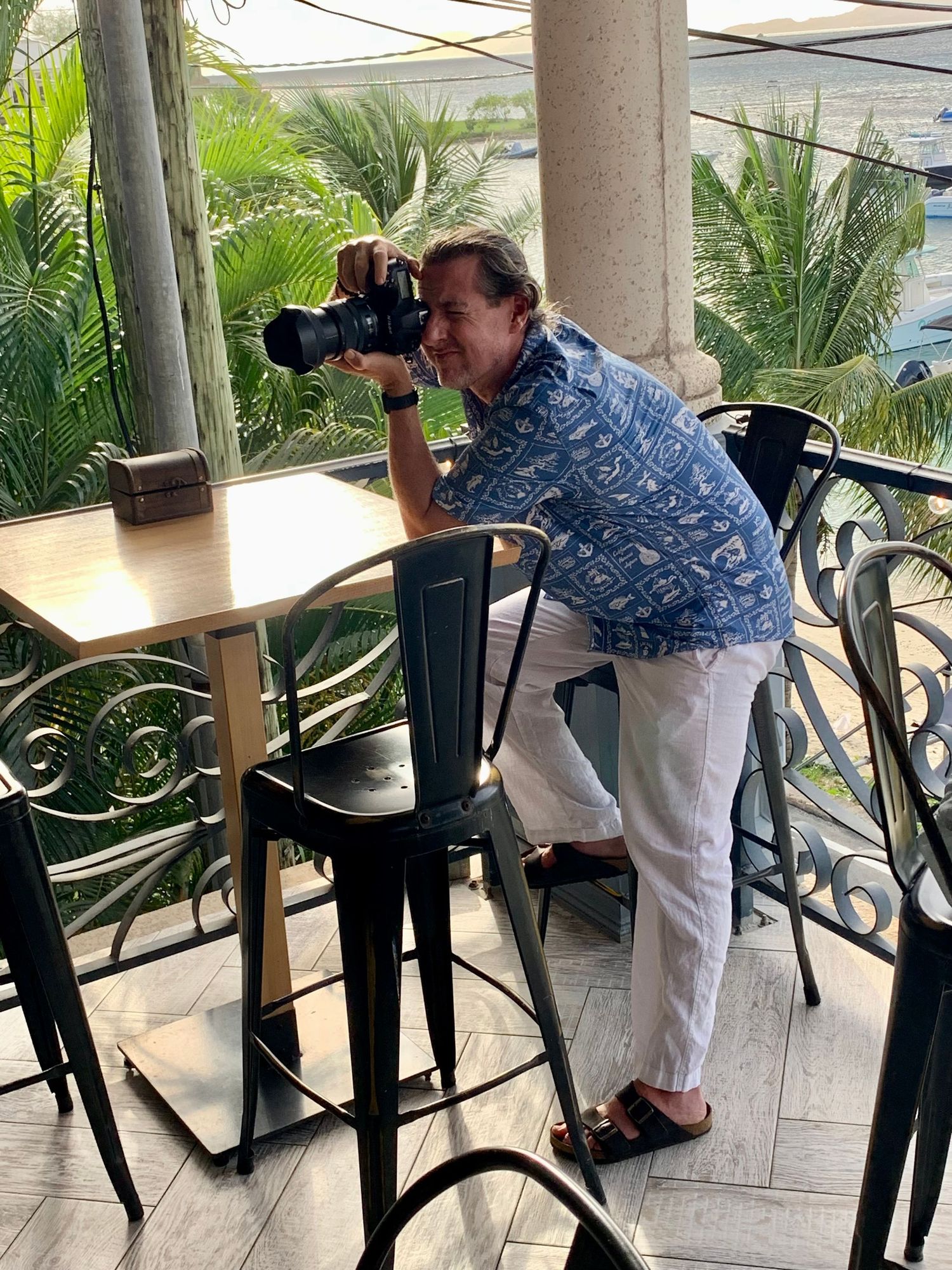 A sequence of images showing Sean Stacey capturing images of someone performing music at a beach bar in St. John.