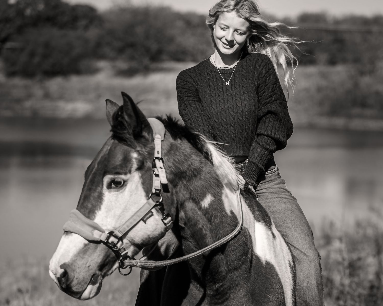 Black and white equestrian portrait series showing riders with horses in outdoor settings by a lake during a horse show in Texas.