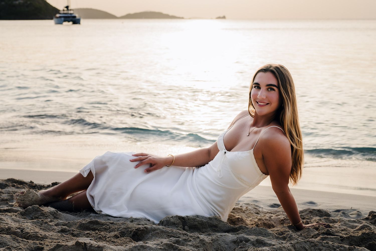 College senior barefoot along St. John shoreline at sunset during destination senior session.