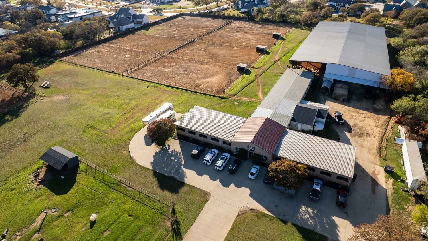 Aerial view of a large equestrian facility with multiple buildings and riding areas during a branding session for Southlake Equestrian barn.