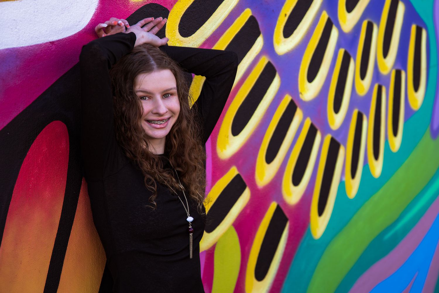 Senior girl poses near historic West 7th St in a graffitied alley for fine art fashion portraits.