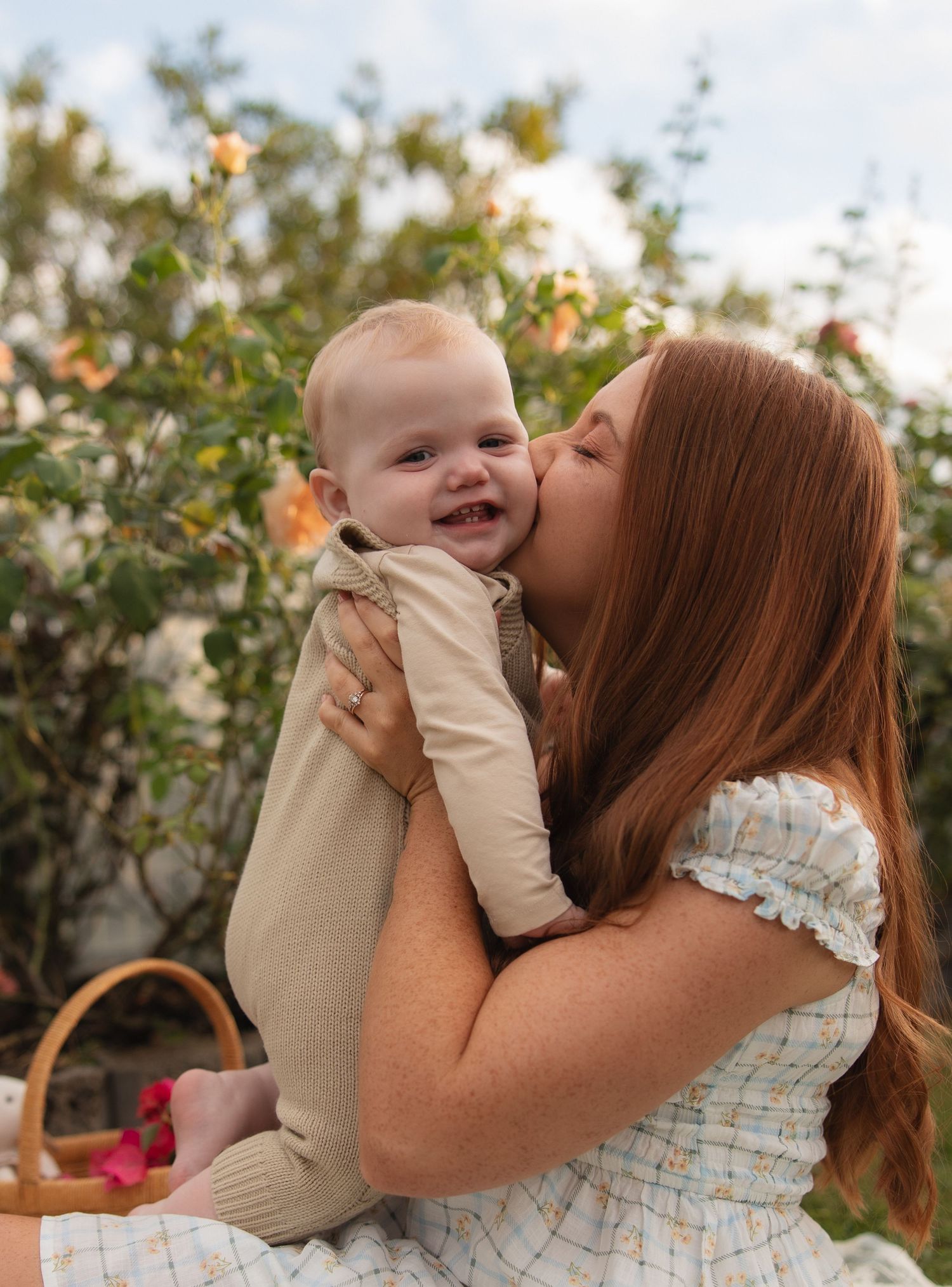 A tender moment shared between parent and child showing kisses and joyful expressions in an outdoor garden setting.