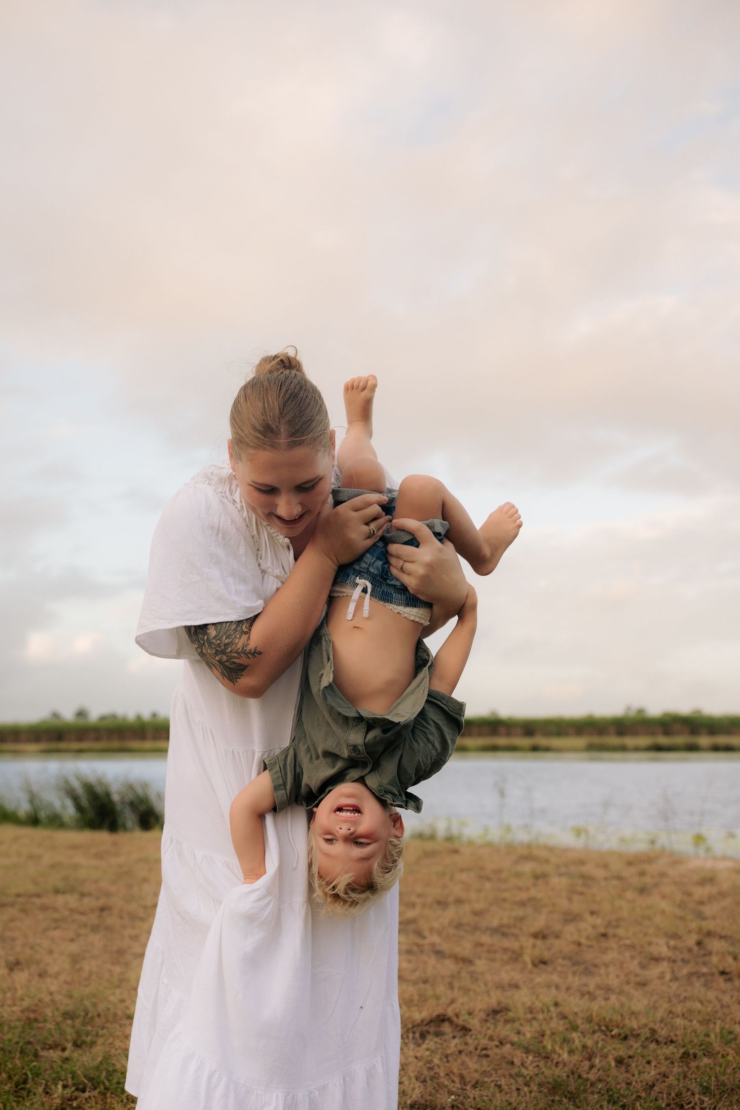 A joyful moment captured as a parent playfully holds a laughing child upside down.
