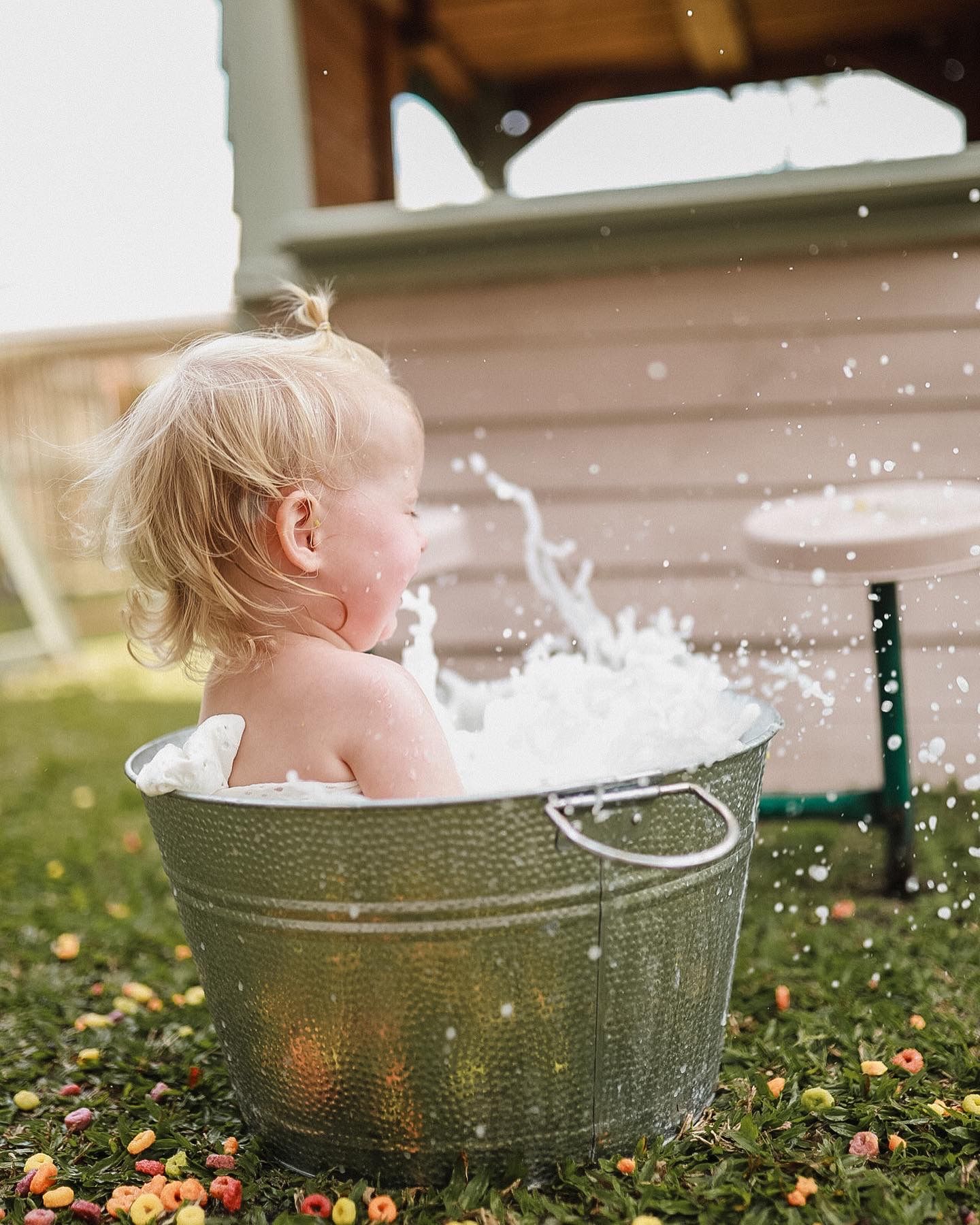 Water splashes around vintage metal tub during outdoor playtime on grass.
