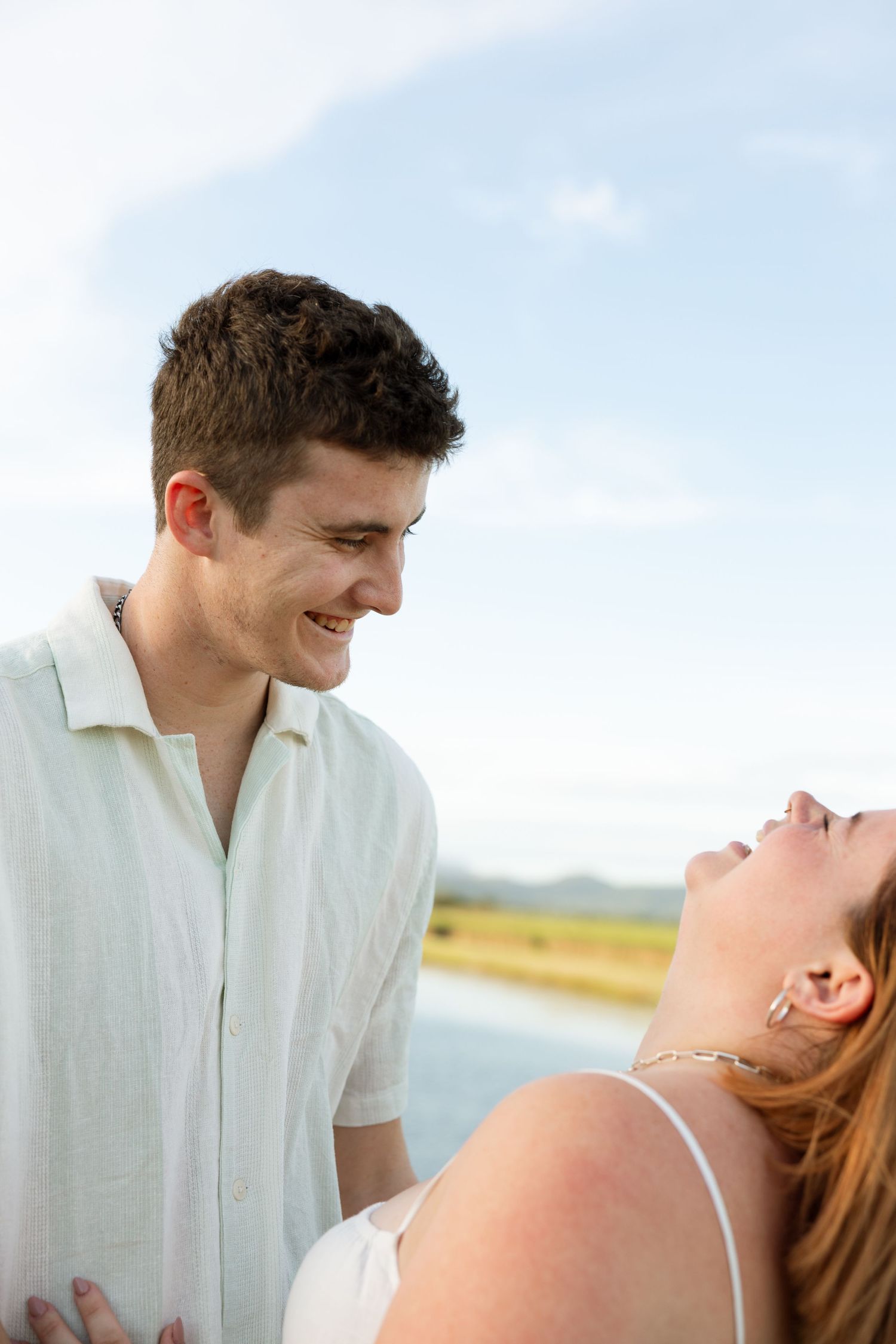 A joyful moment shared between a couple laughing together by a lake.