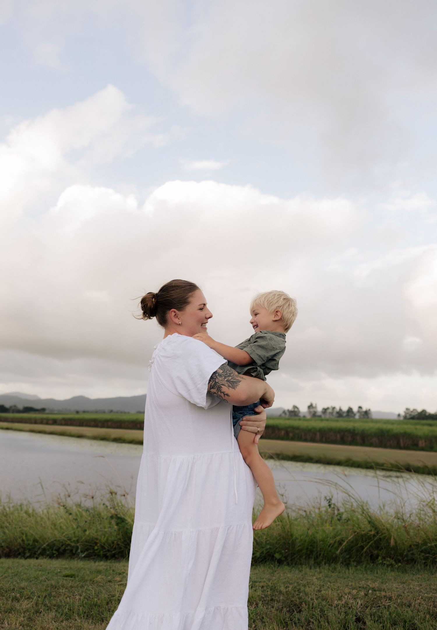 A touching moment outdoors with mountains and water in the background.