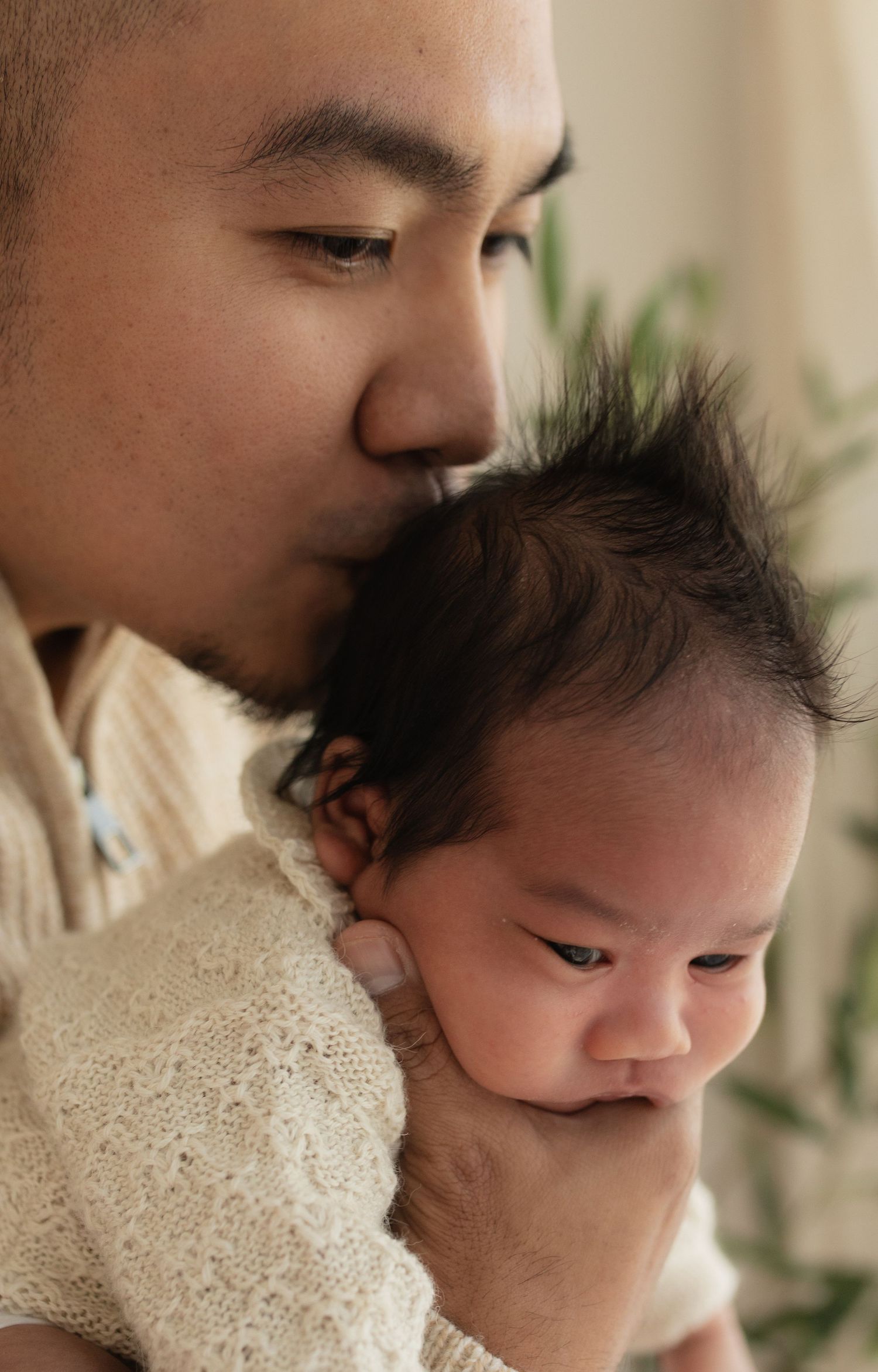 An intimate close-up of a parent giving a gentle kiss to their baby's head.