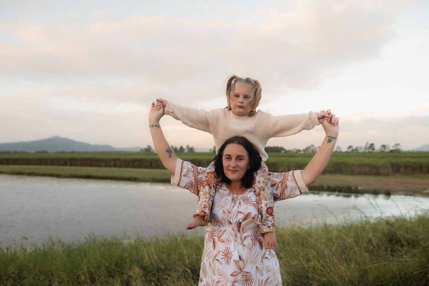 Joyful moment shared between parent and child against scenic lakeside backdrop.