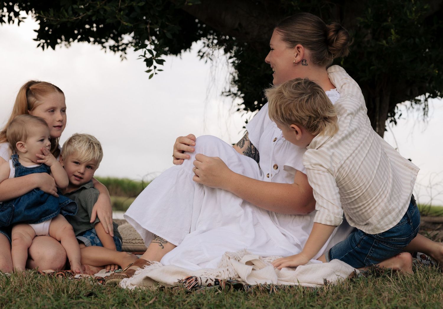 Family sharing a relaxed picnic moment under a shady tree.