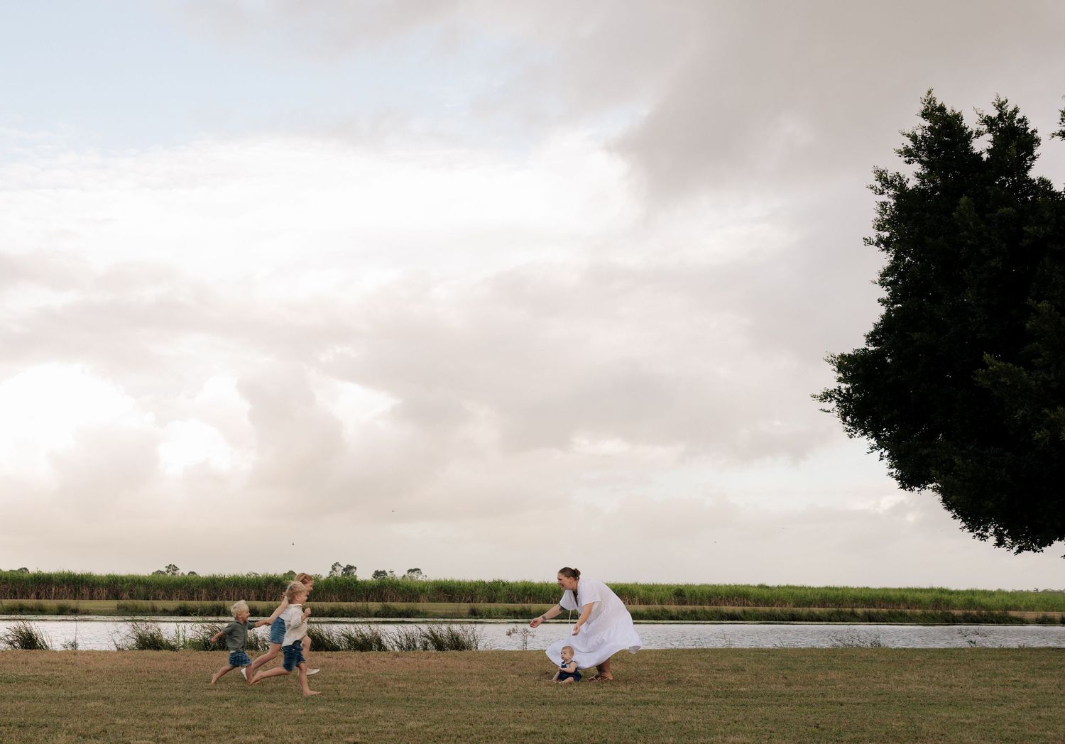 Family silhouetted against a dramatic sky during sunset by the water.