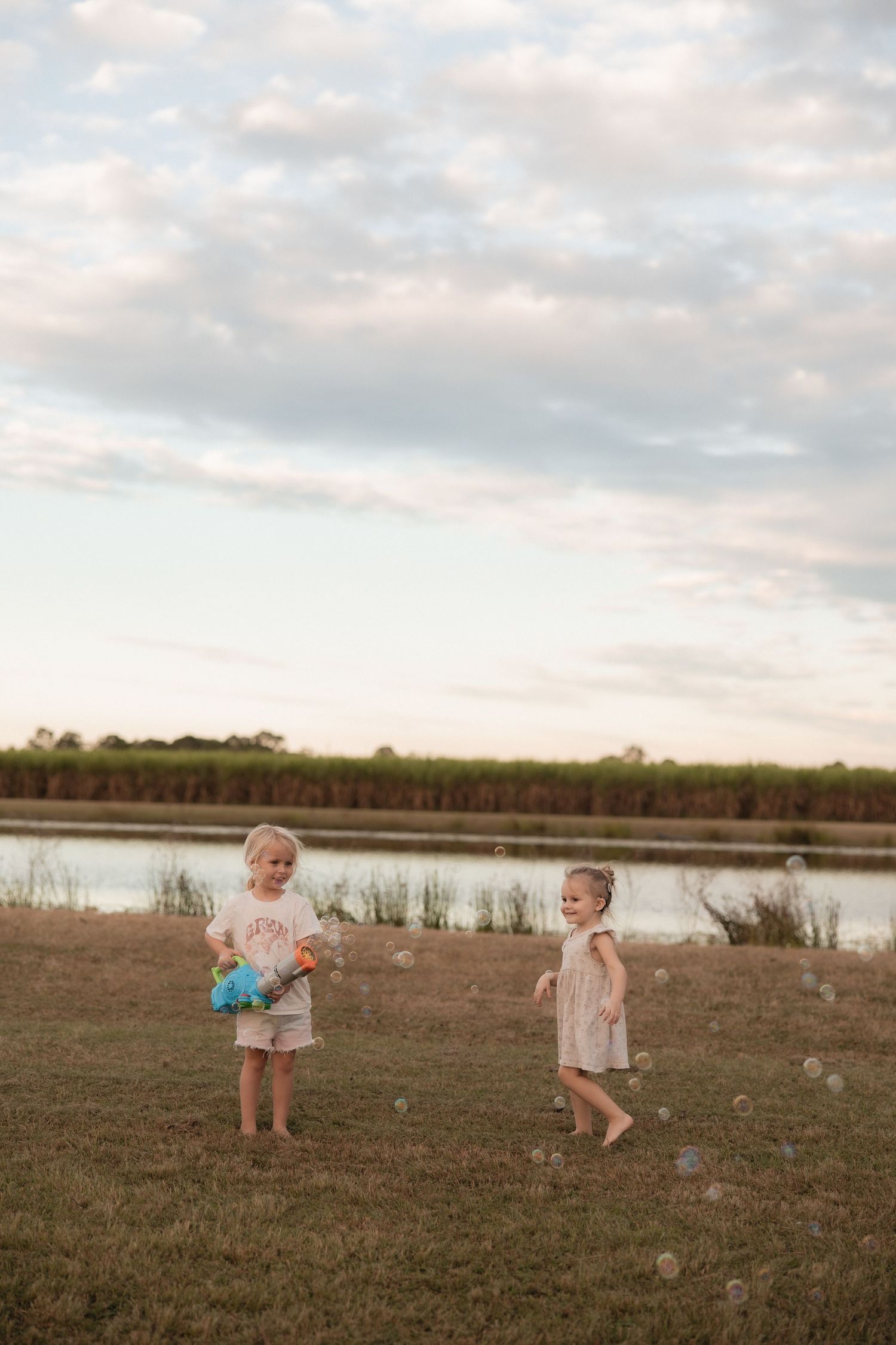 Two young children playing together by a lake at dusk.
