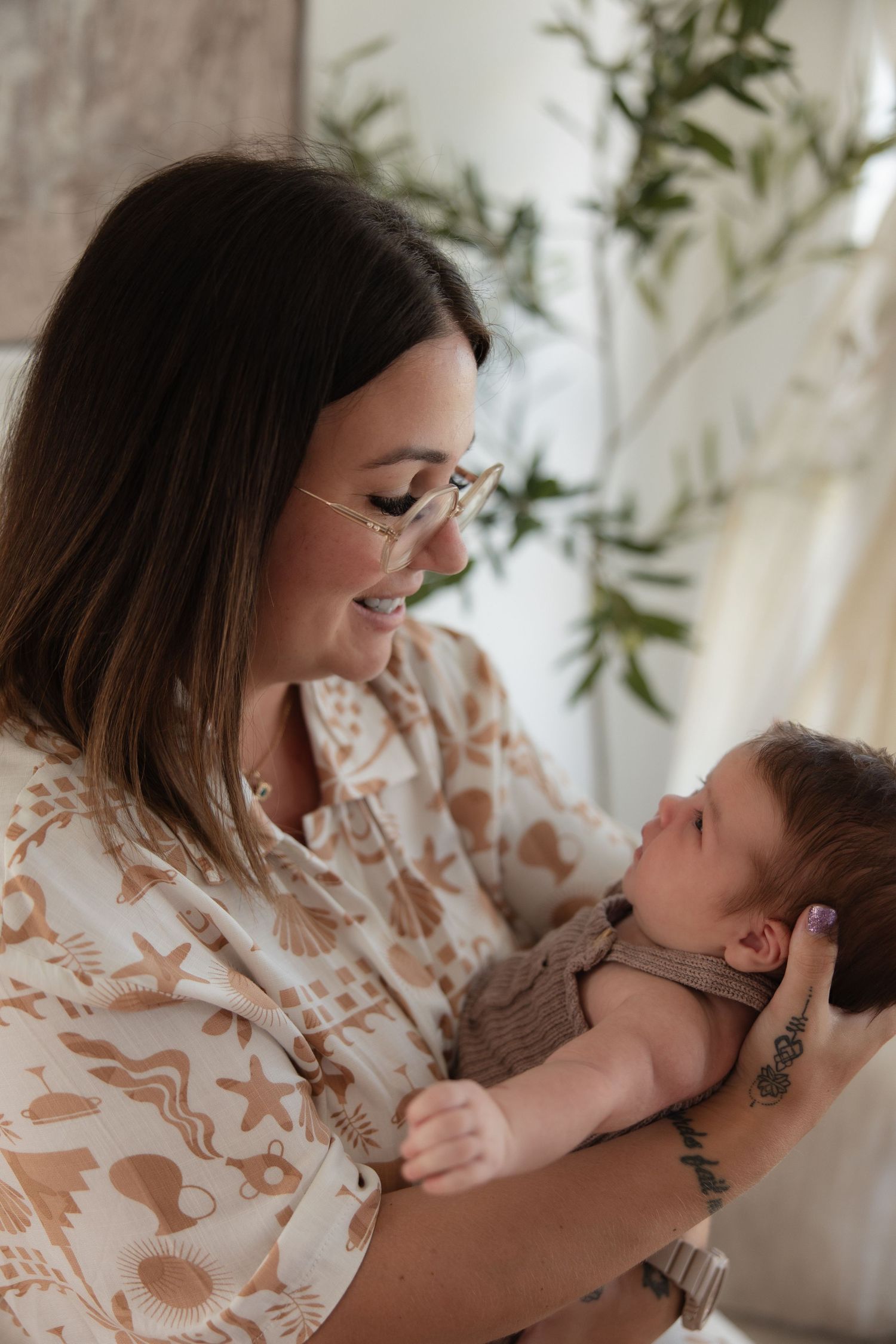 A heartwarming moment between parent and baby in a sunlit room with plants.