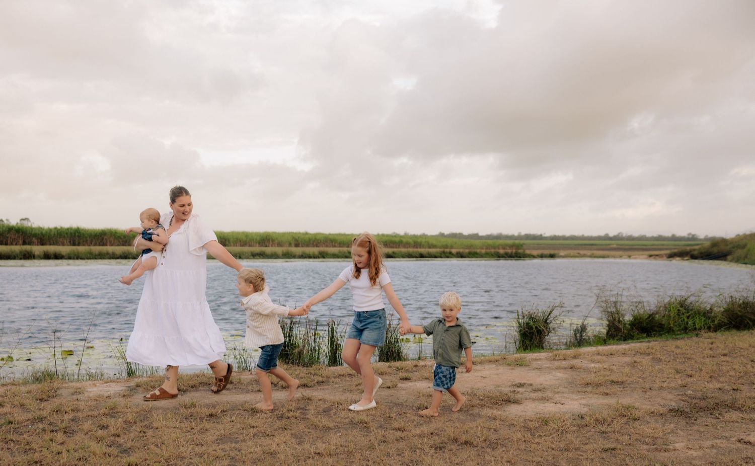 Family enjoying playful moments together by the water's edge at sunset.
