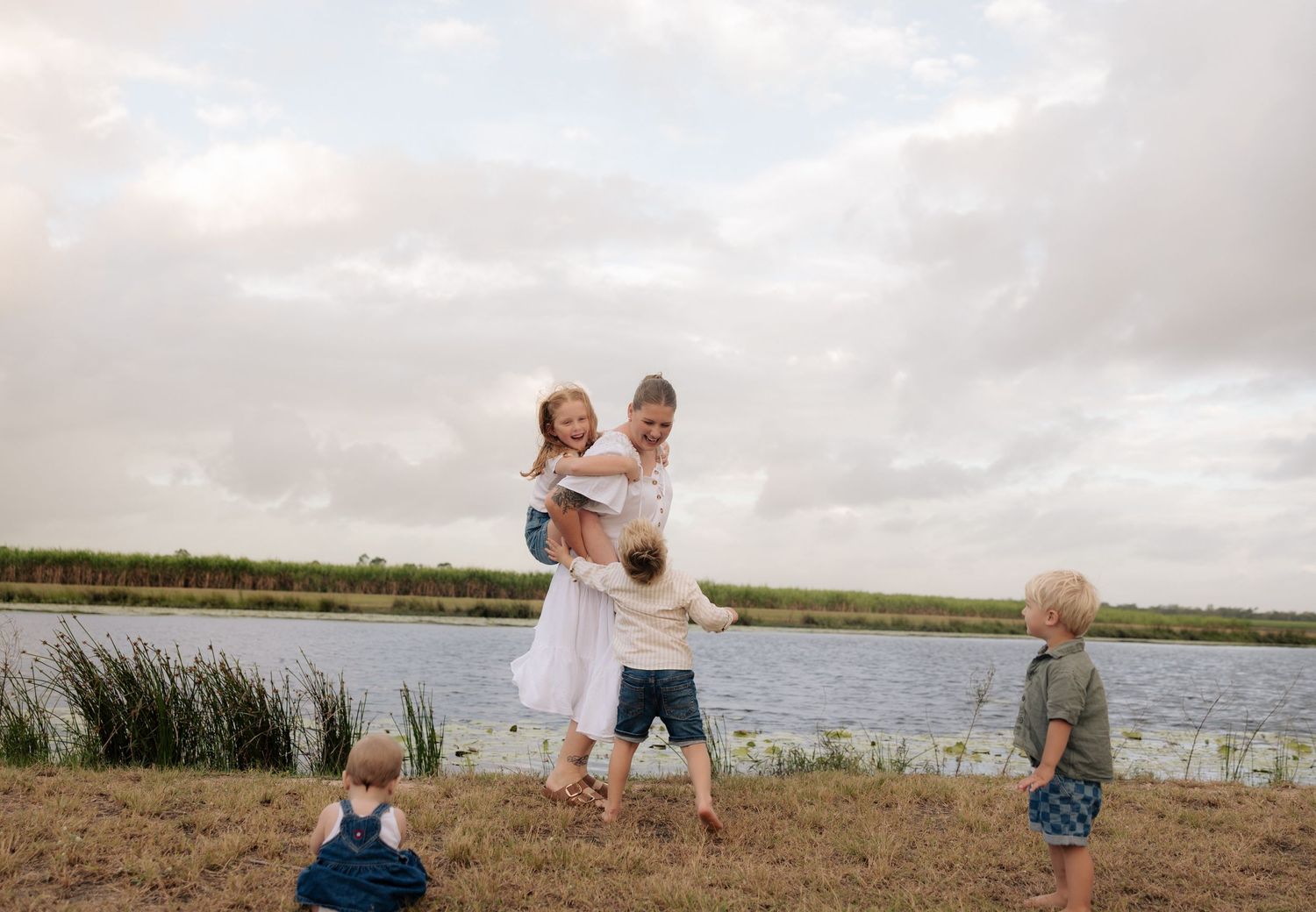 Family enjoying a relaxing moment together by a serene lake on a cloudy day.
