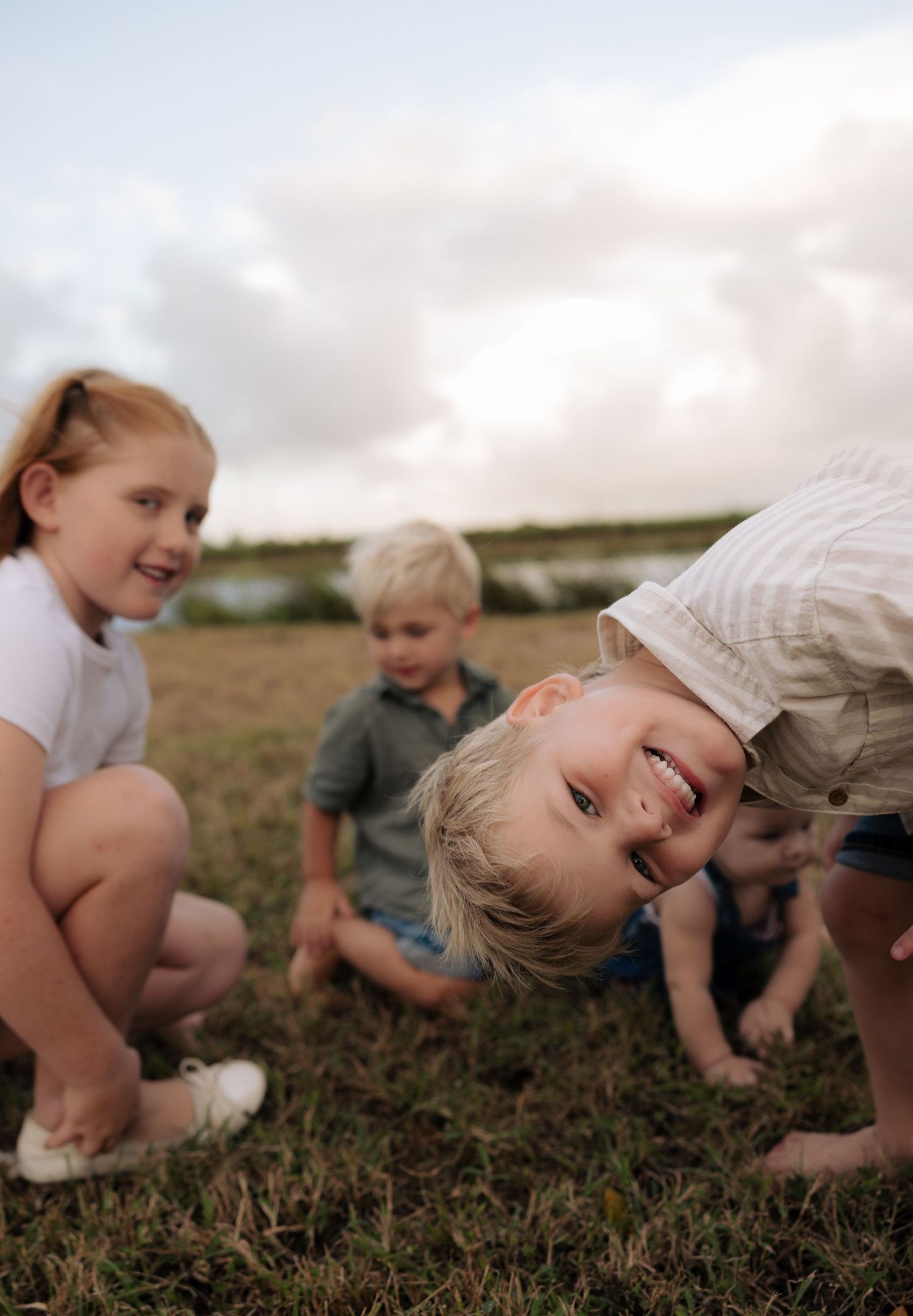 Children playing and laughing together in a grassy field at sunset.