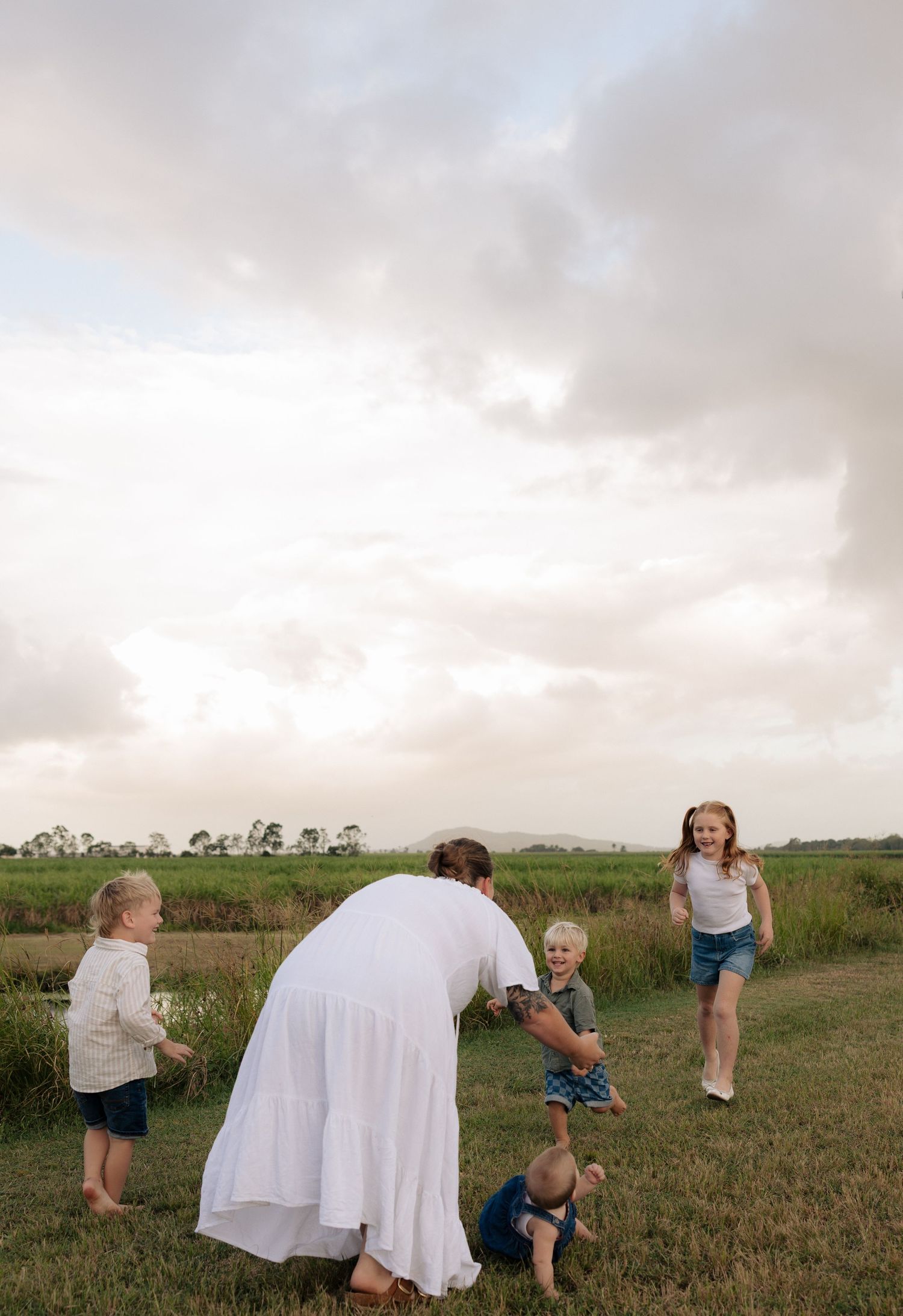 Playful family interaction on grassy terrain near a lake.