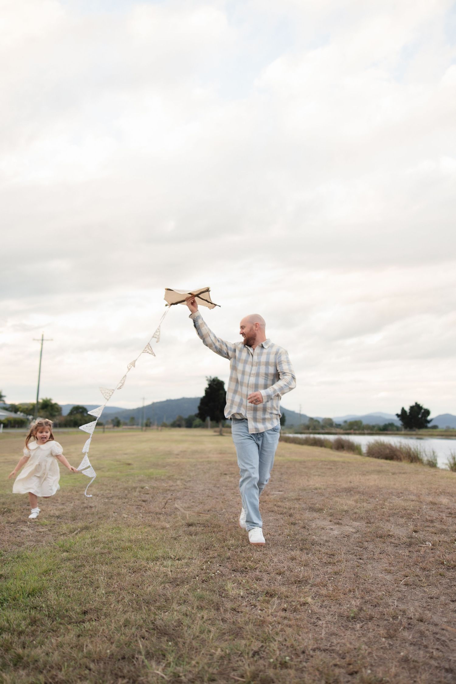 Someone frolics joyfully across an open field near the mountains wearing jeans and a white shirt in a playful series.