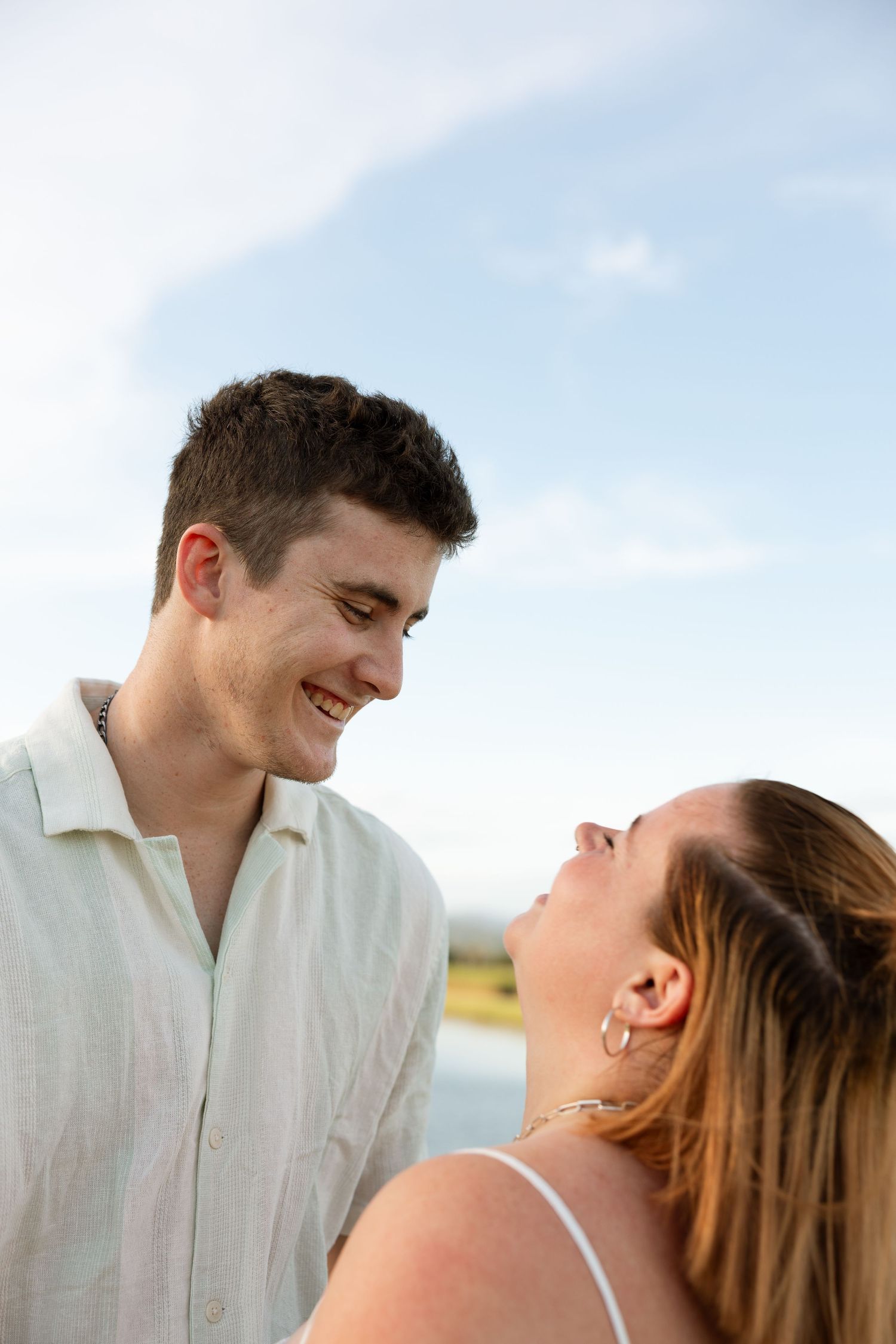 A couple sharing a light-hearted moment together by a lake during sunset.