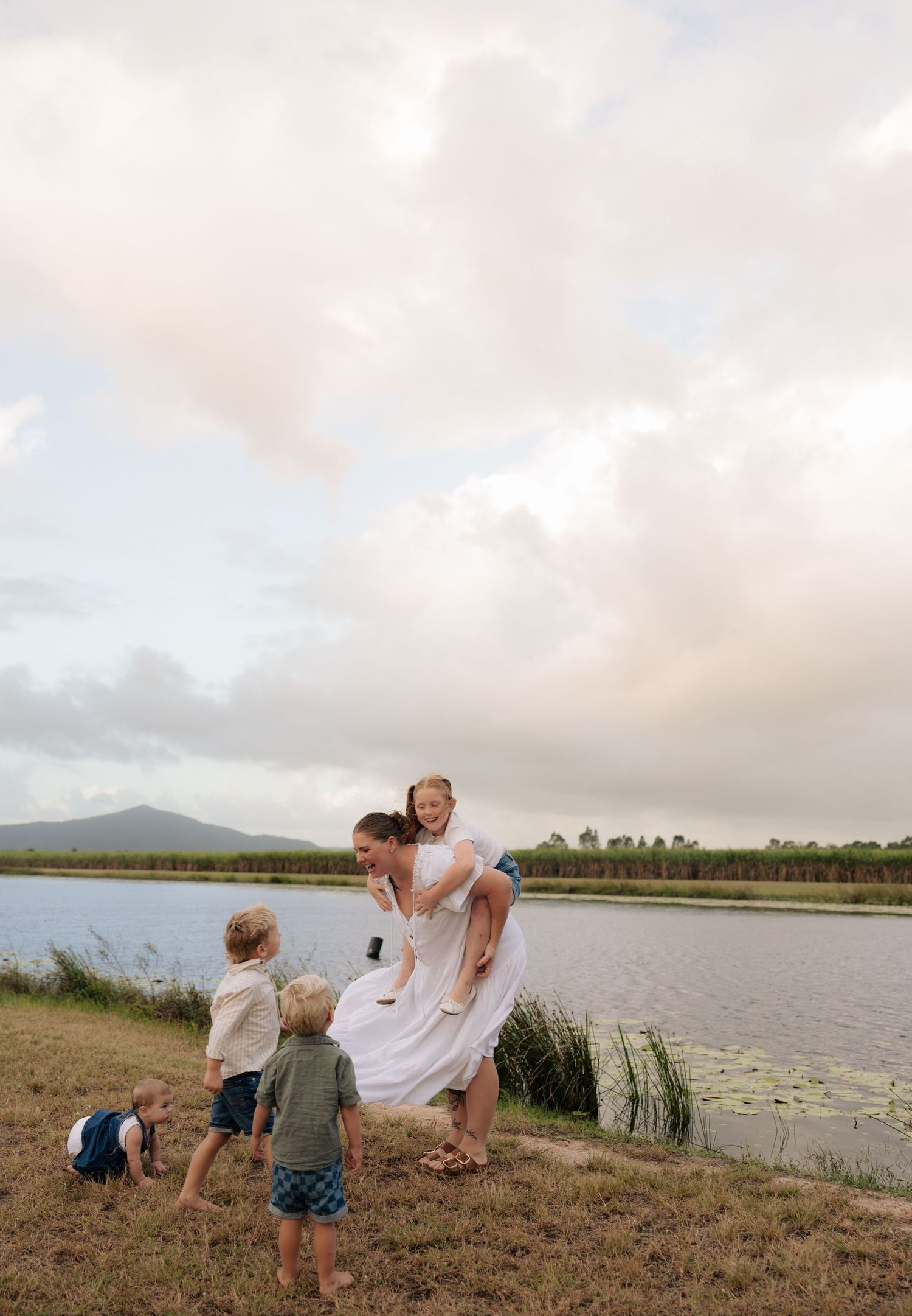 Family enjoying a playful moment together by a scenic lake during sunset.
