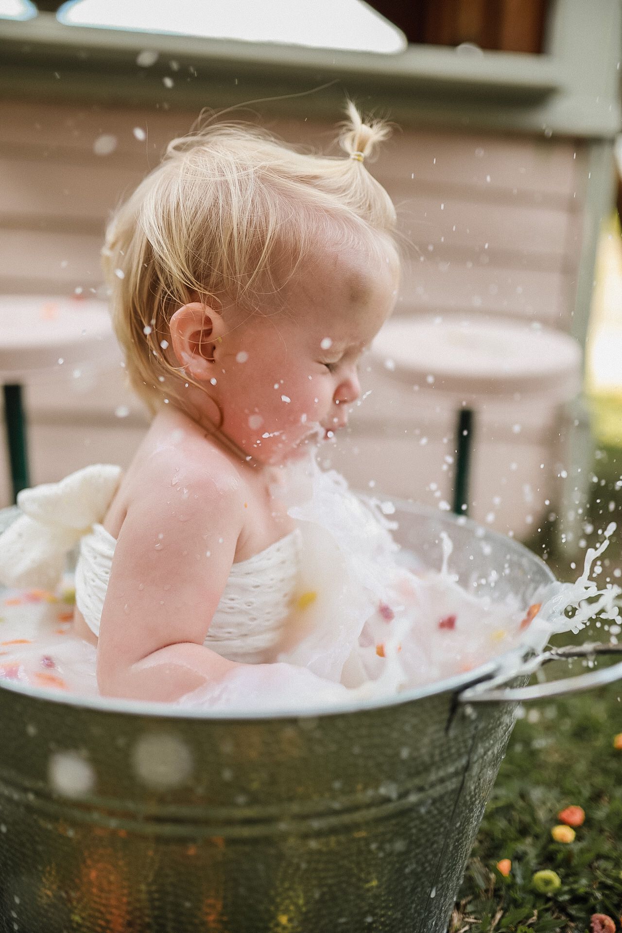 Splashing water flies around metal tub during outdoor bath time photoshoot.