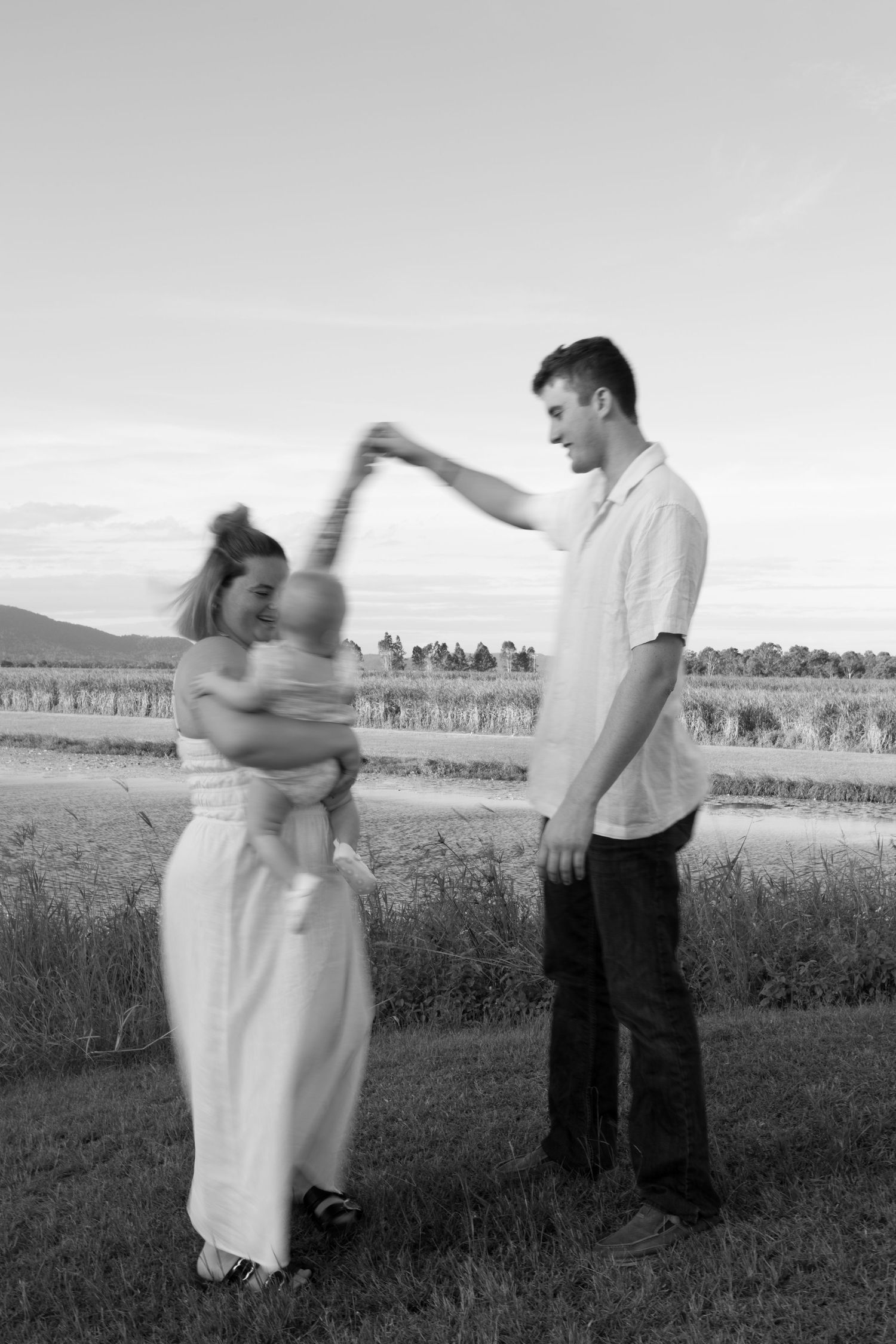 A couple dancing together in a field with mountains visible in the background.