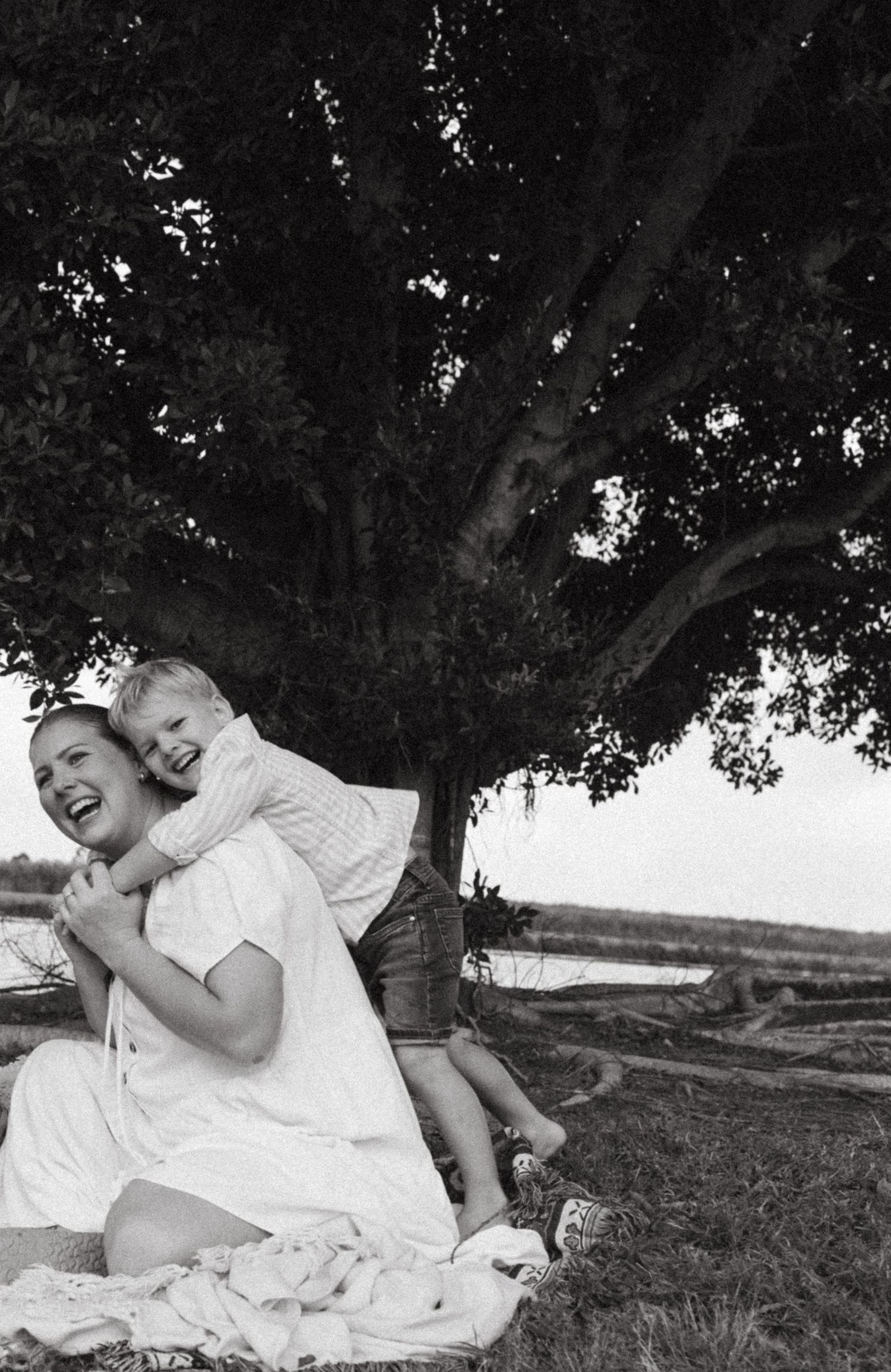 Black and white capture of a playful moment under a large tree.
